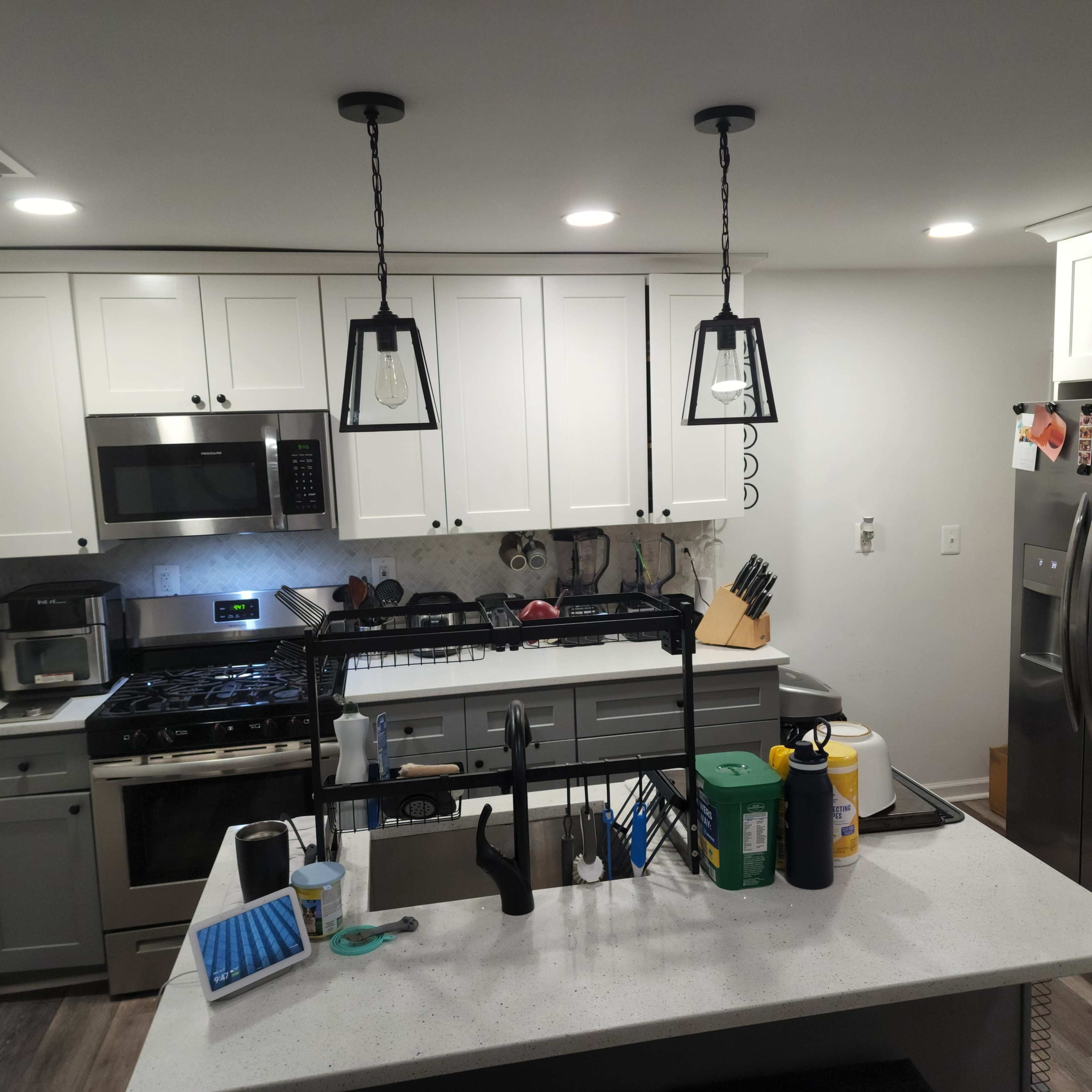 A modern kitchen features white cabinets, stainless steel appliances, and a central island with pendant lighting.