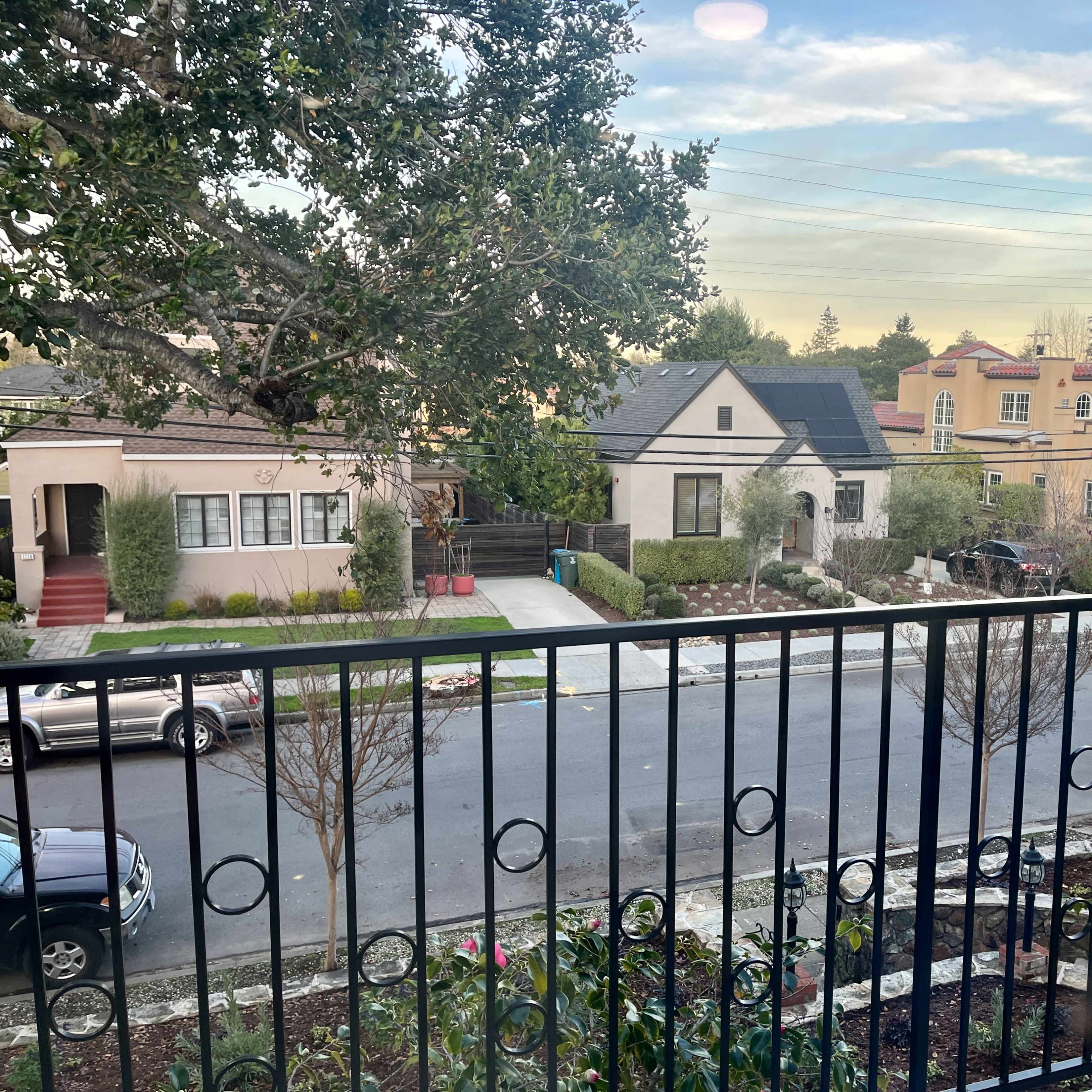 A view from a balcony overlooking a suburban street with several houses and well-maintained lawns.