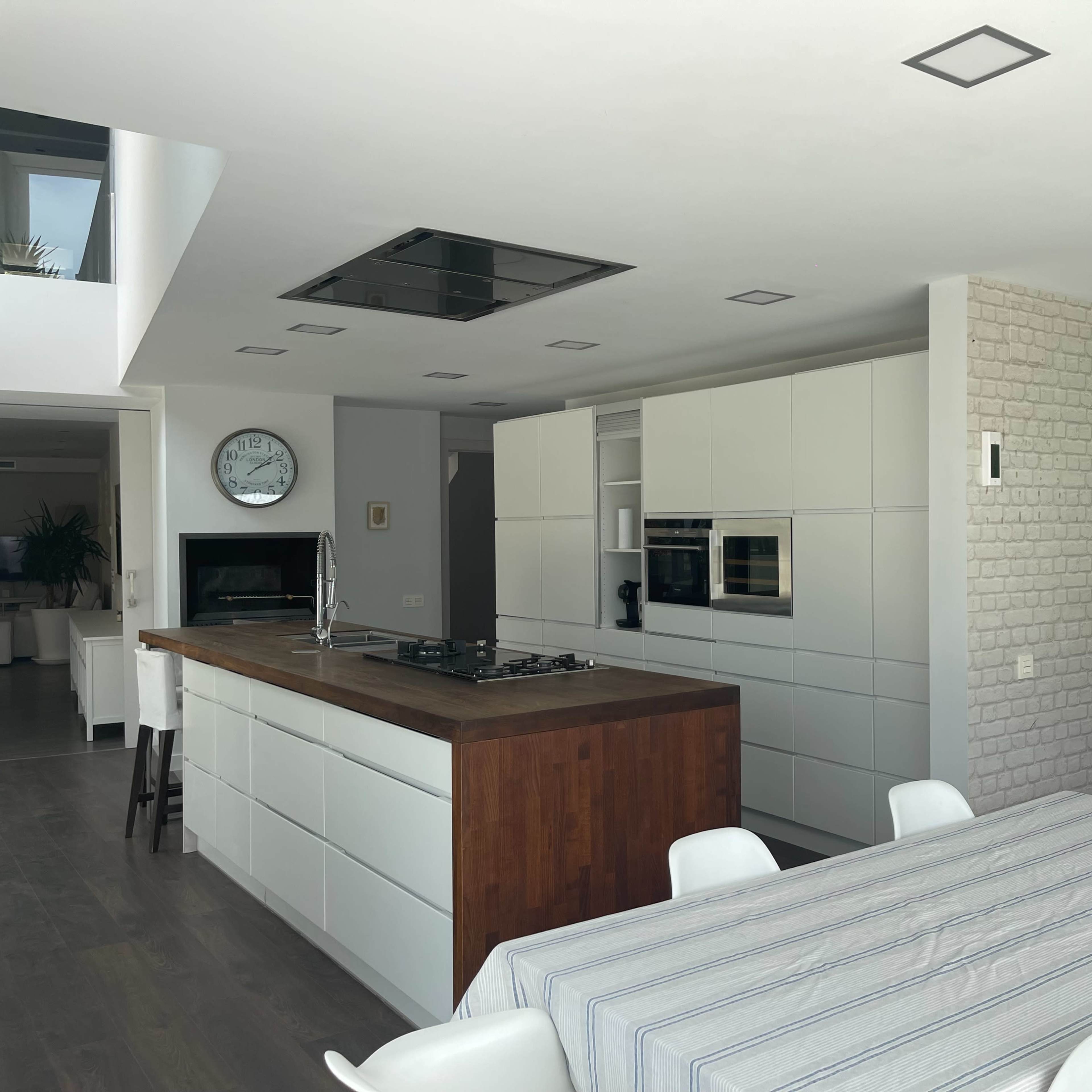 A modern kitchen features white cabinetry, a wooden island, and a wall with a world map.
