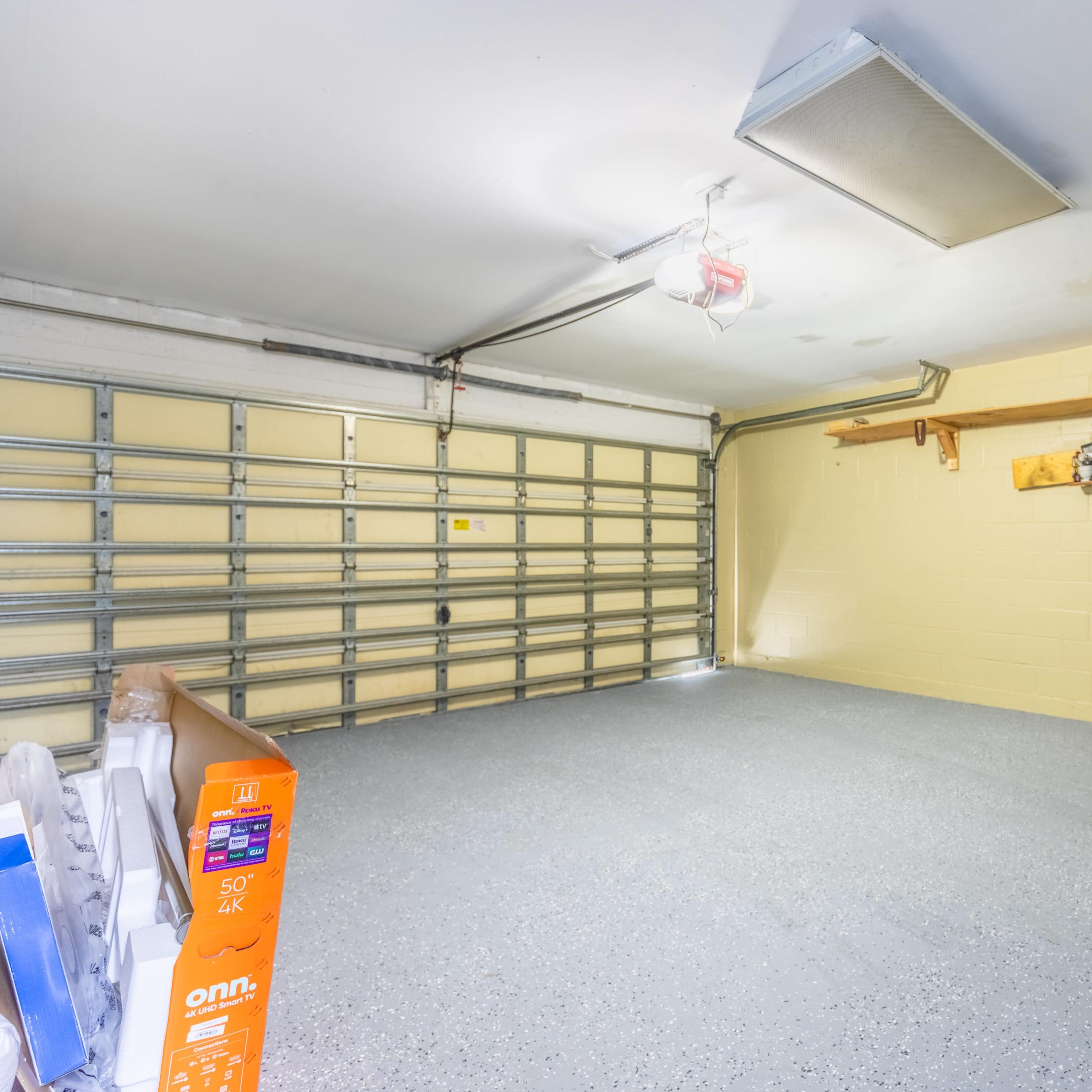 An empty garage with a concrete floor and a large garage door on one side.