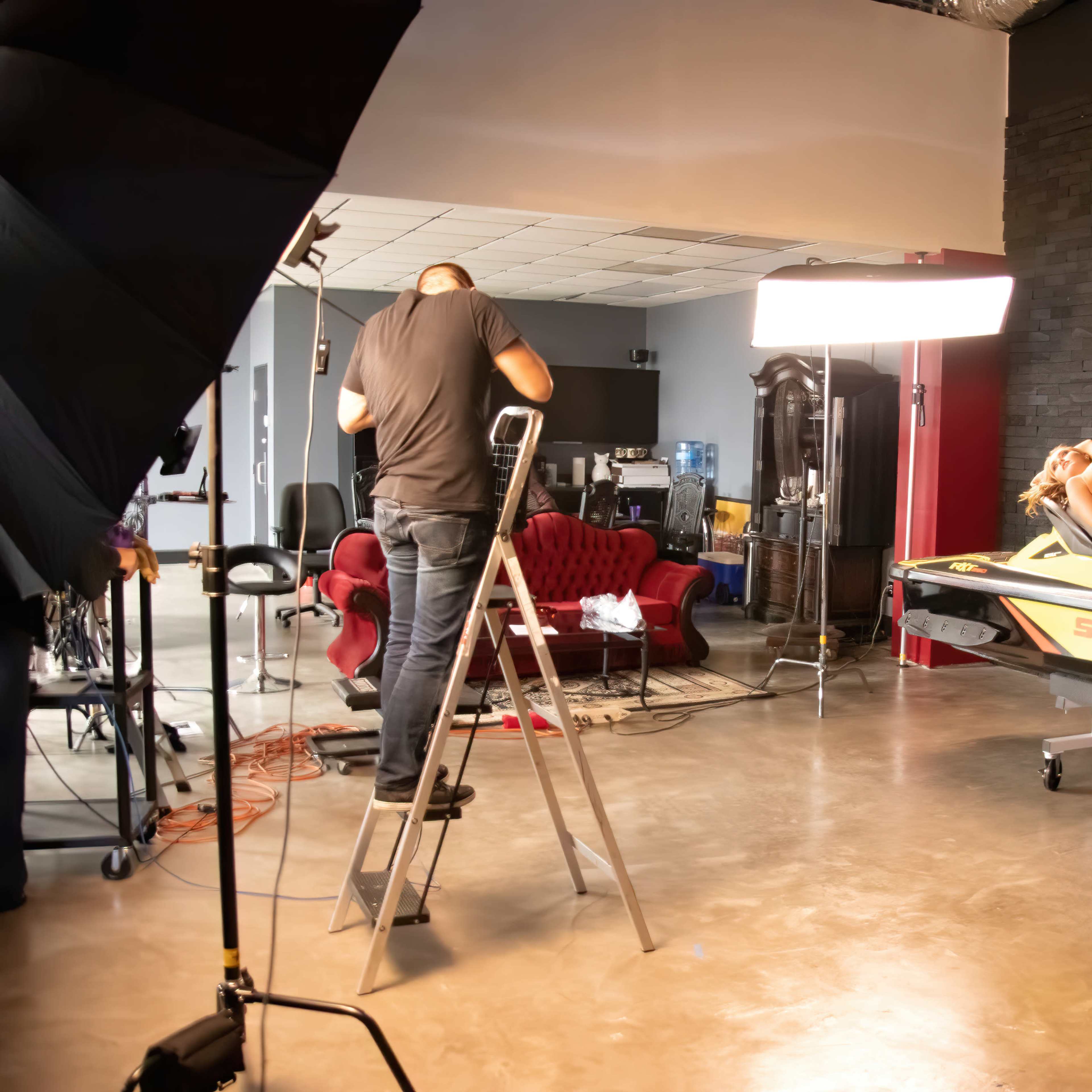 A model poses on a yellow jet ski in a studio setting, while a photographer adjusts equipment nearby.