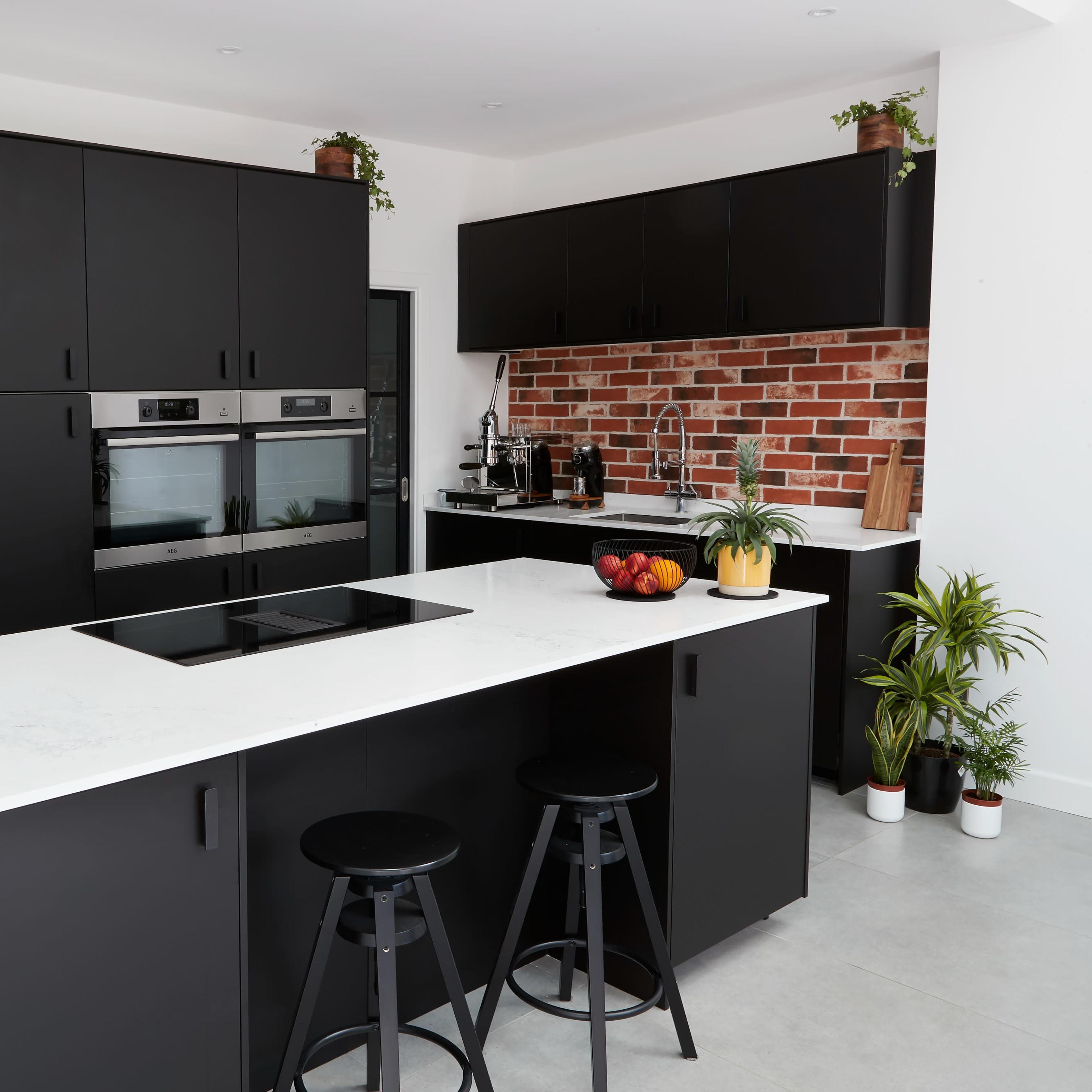 A modern kitchen featuring black cabinetry, stainless steel appliances, and a quartz countertop with a central cooking island.