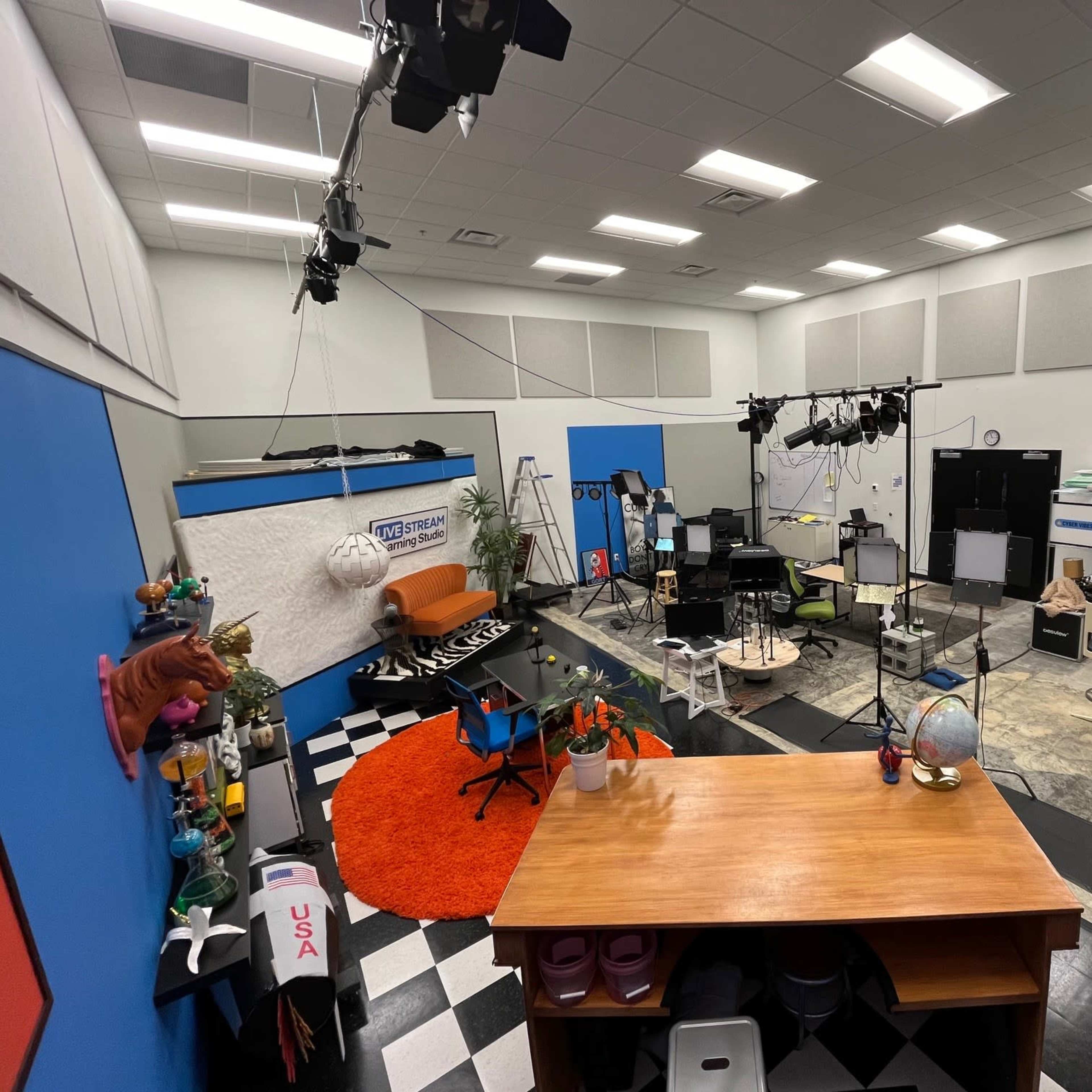 A spacious studio with colorful walls, various lighting equipment, and multiple set pieces arranged for filming.