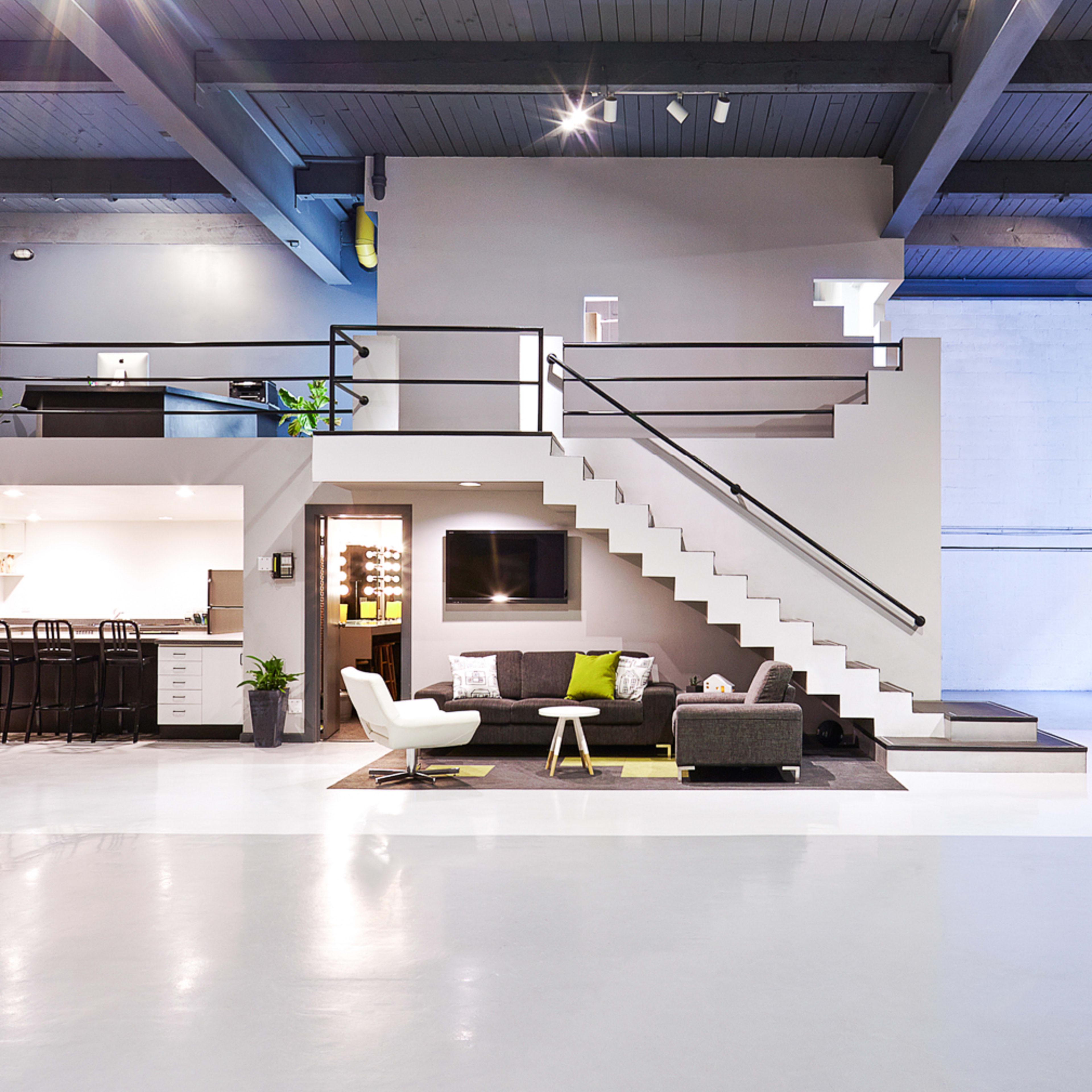 A spacious, modern open-concept living area with a kitchen, a staircase, and various seating arrangements.