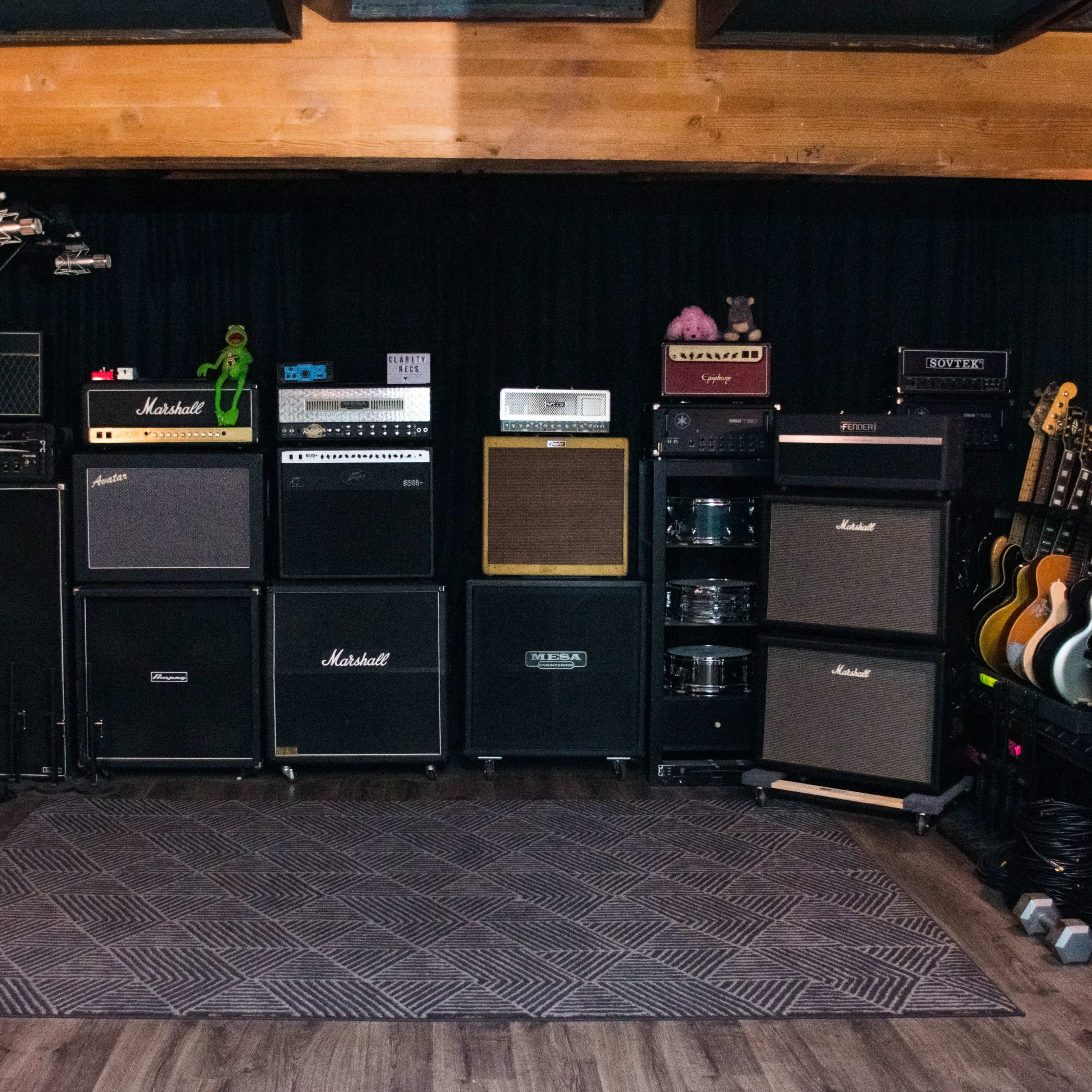 A music studio setup with various amplifiers and electric guitars arranged along a wall.