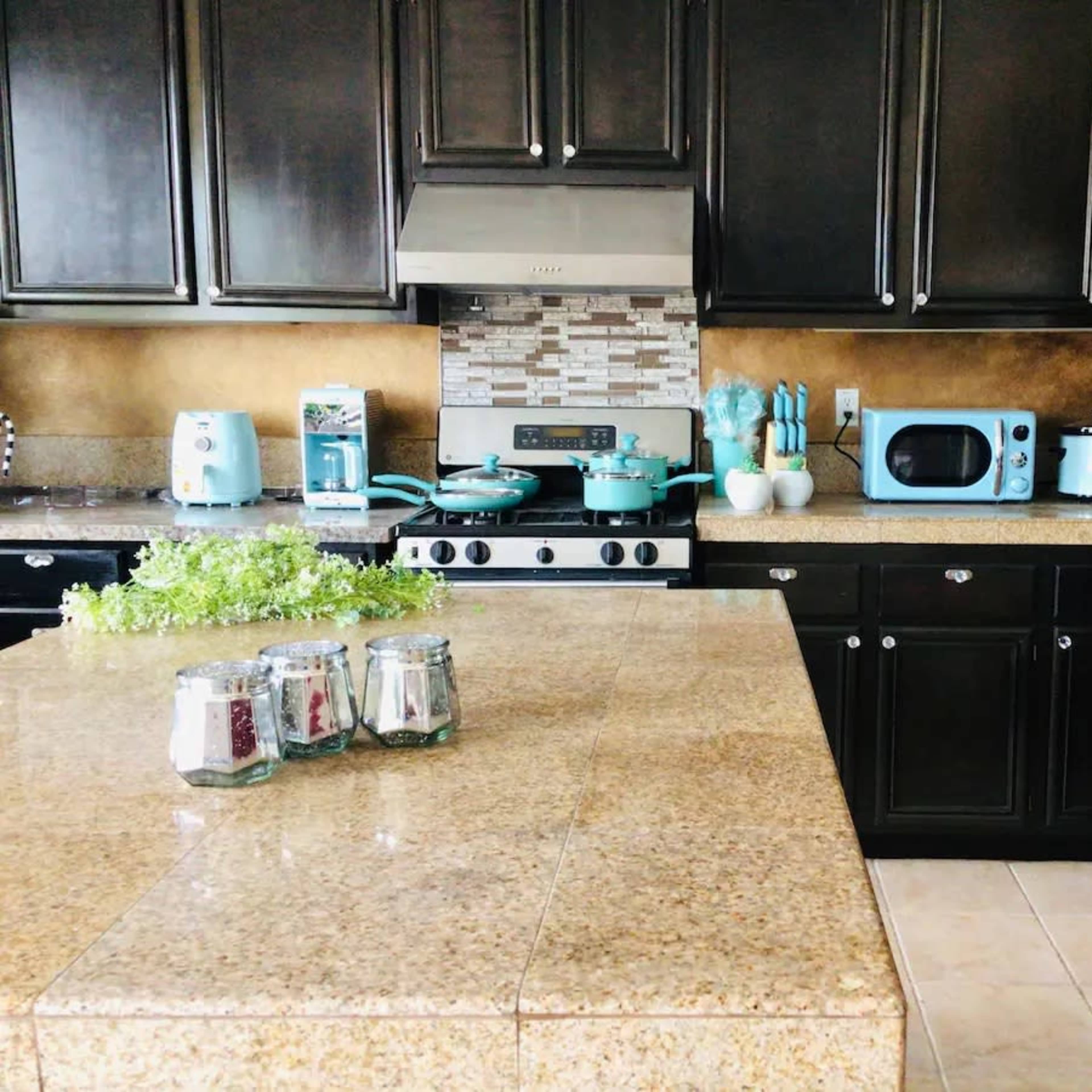 The kitchen features dark cabinets, a granite countertop, and vintage-style turquoise appliances against a tiled backsplash.