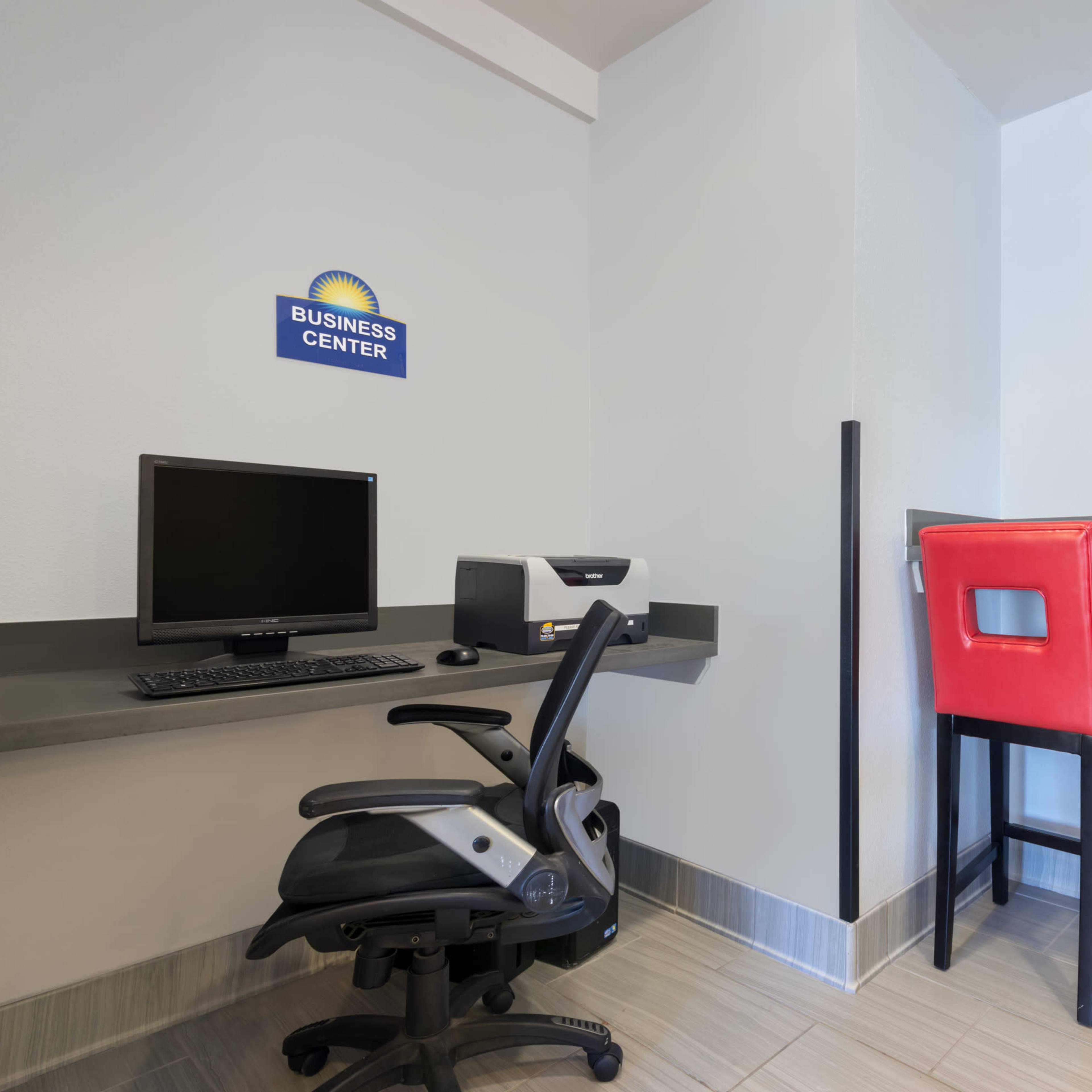 A business center with a computer workstation and two red barstools at a counter.