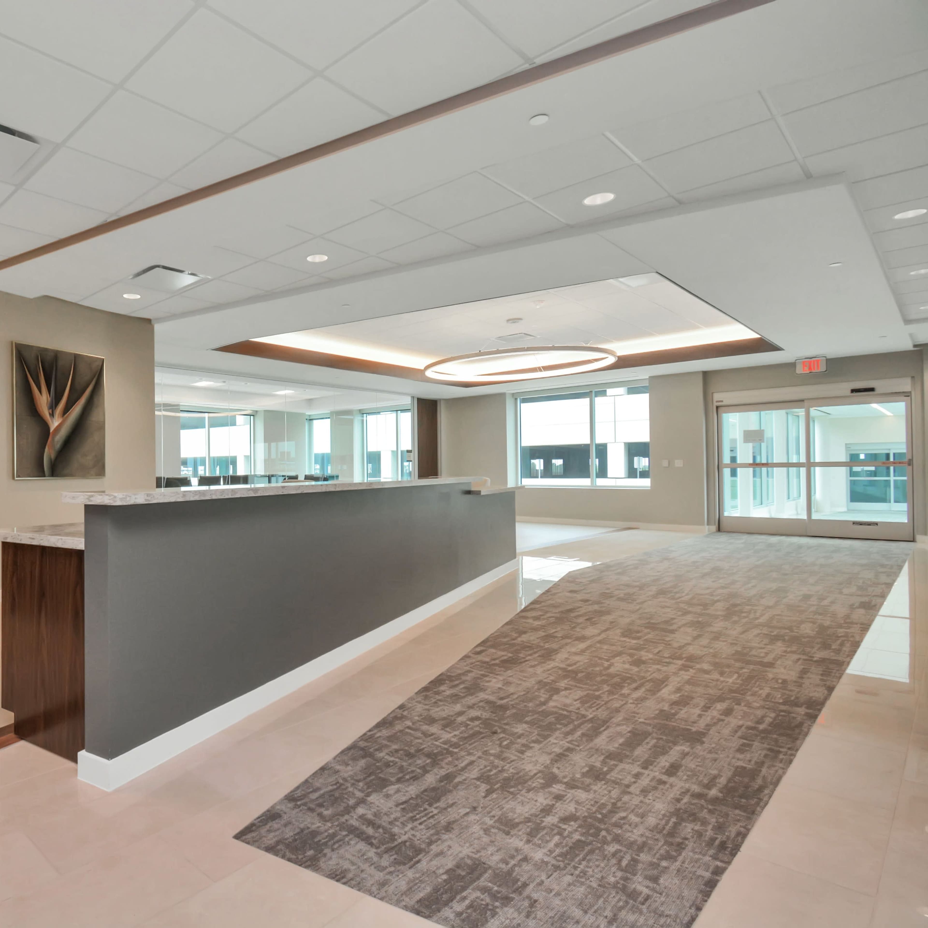 A modern, open office reception area with a long counter and large windows.