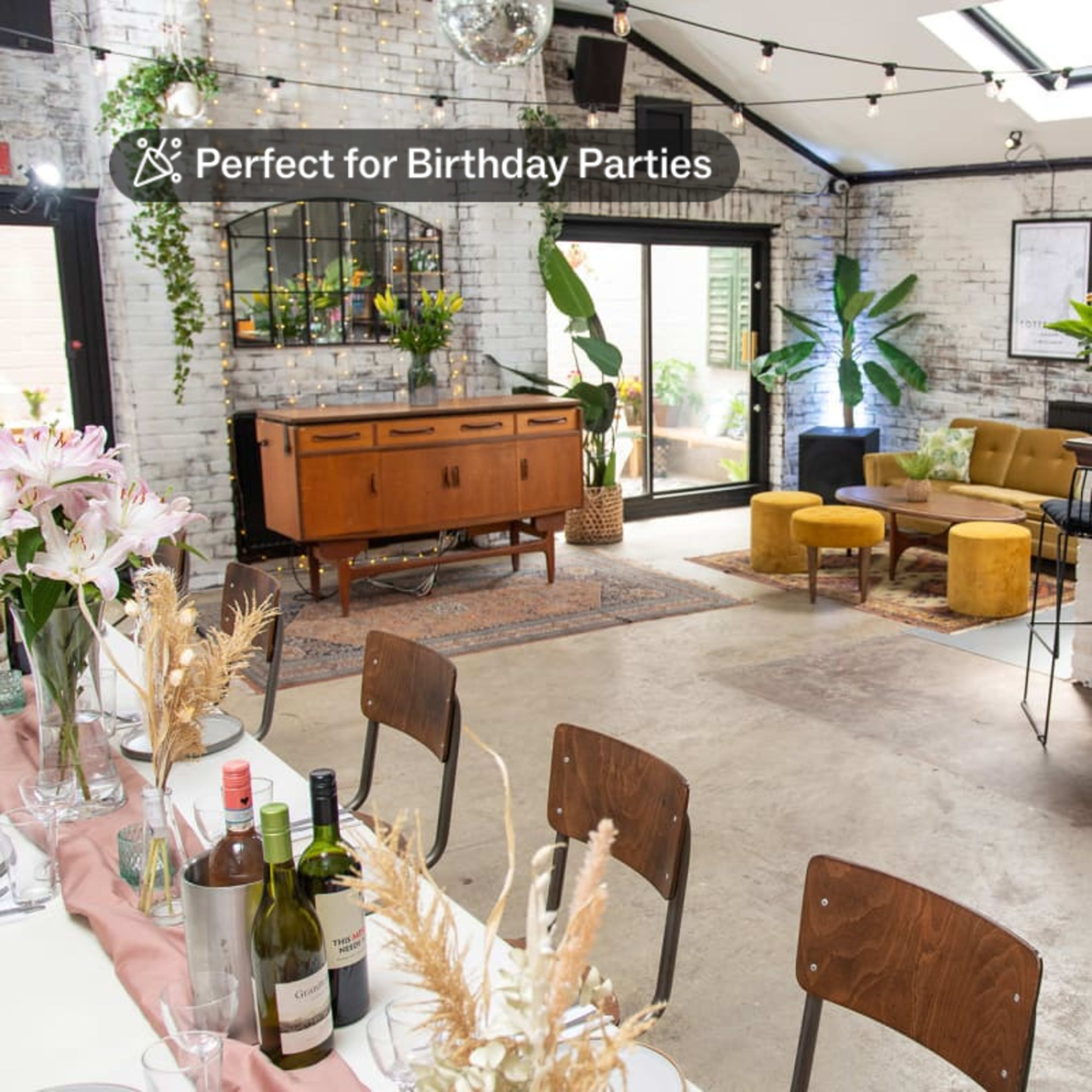 A spacious, decorated interior with a bar, seating area, and a long dining table set for an event.