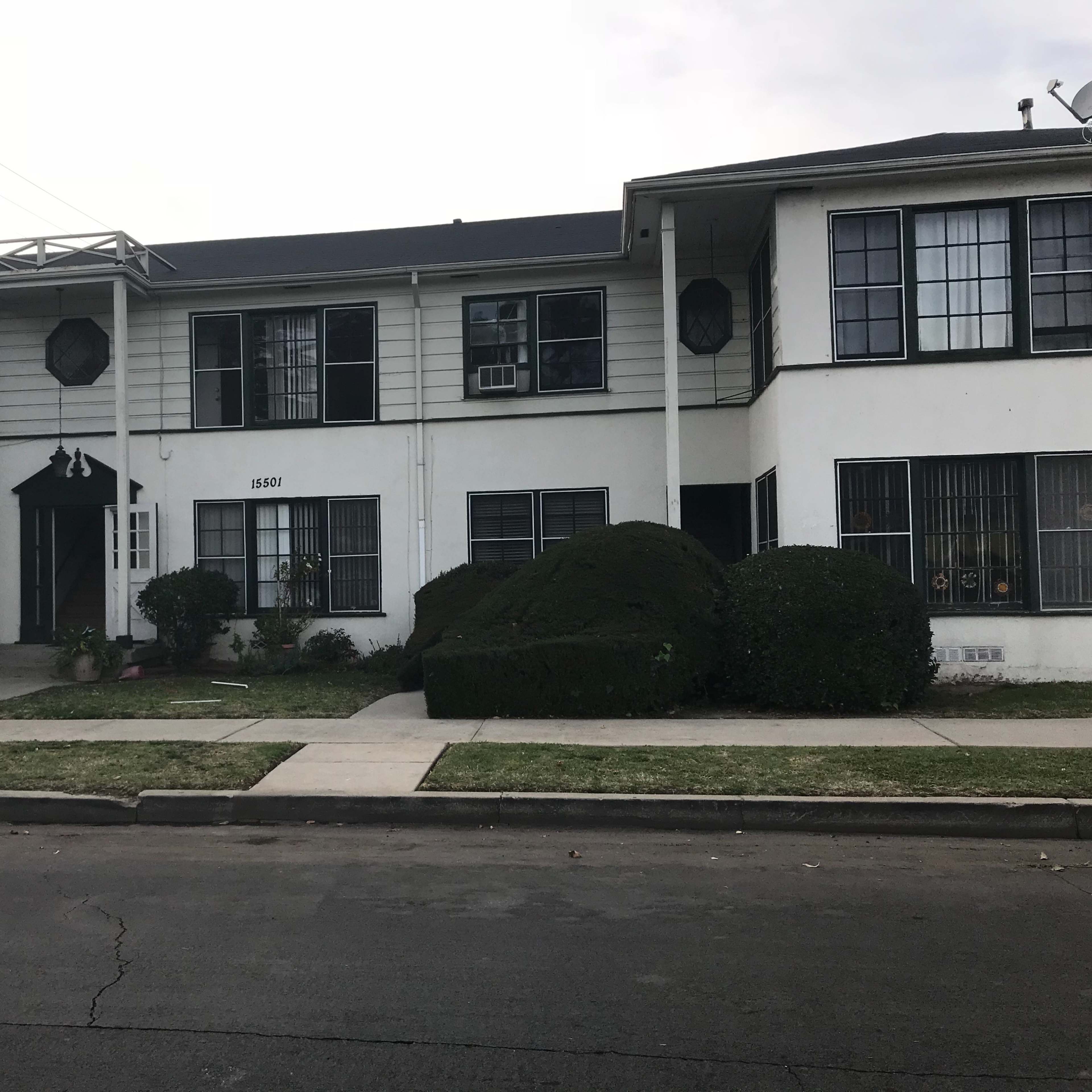 A two-story residential building with a front lawn and sidewalk is shown.