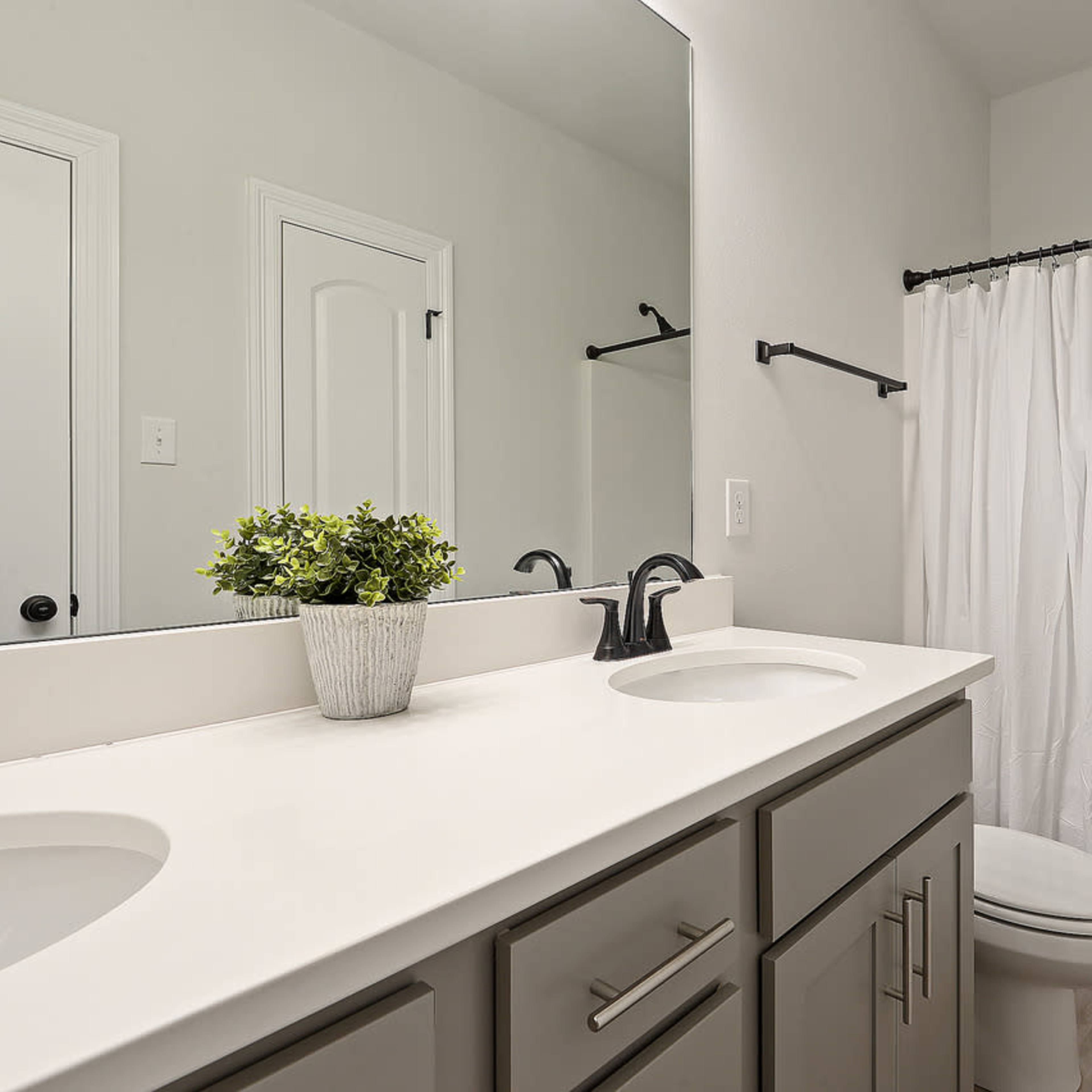A modern bathroom featuring a double sink vanity, a shower and bathtub combination, and light-colored walls.