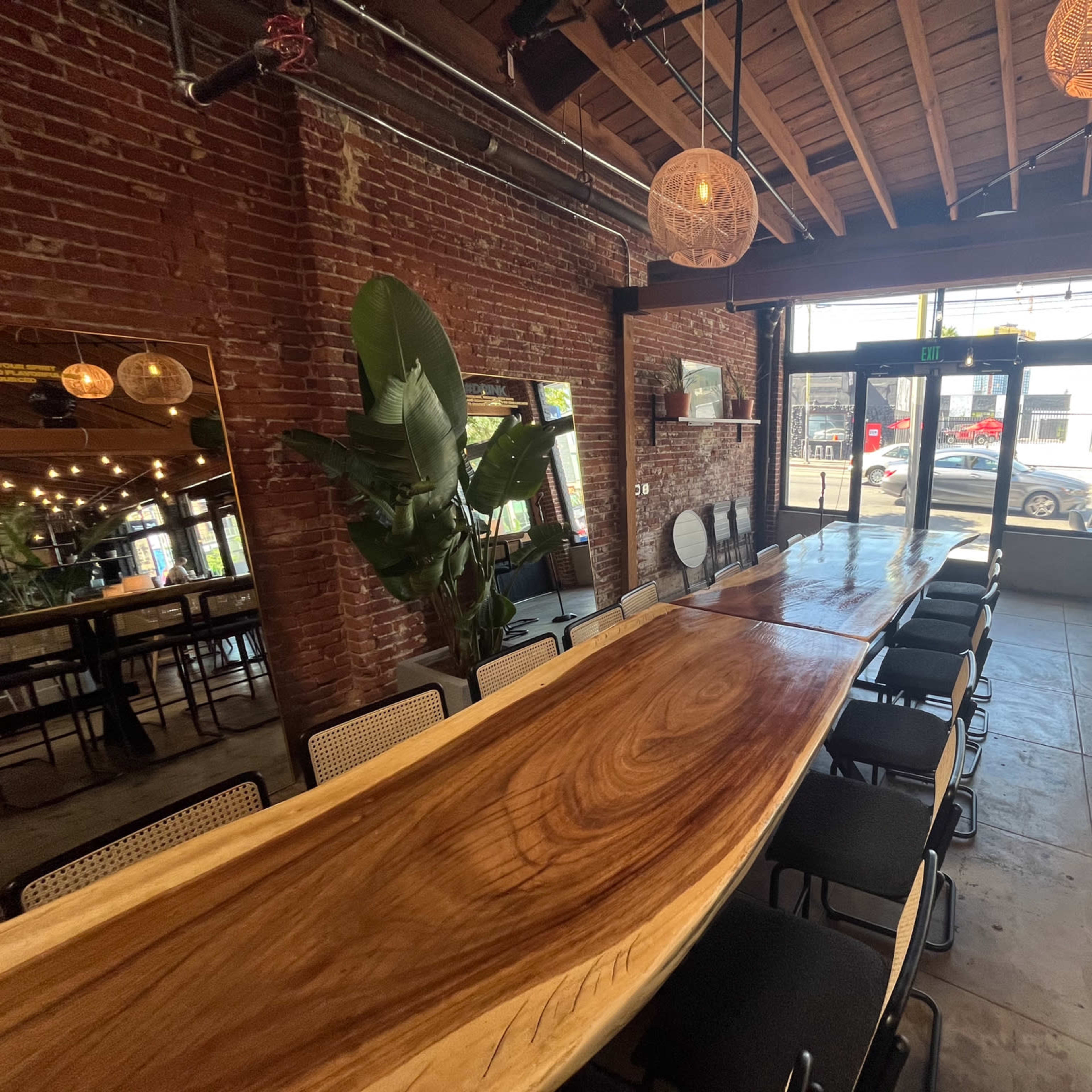 A dining area with a large wooden table, surrounded by chairs, exposed brick walls, and pendant lighting.