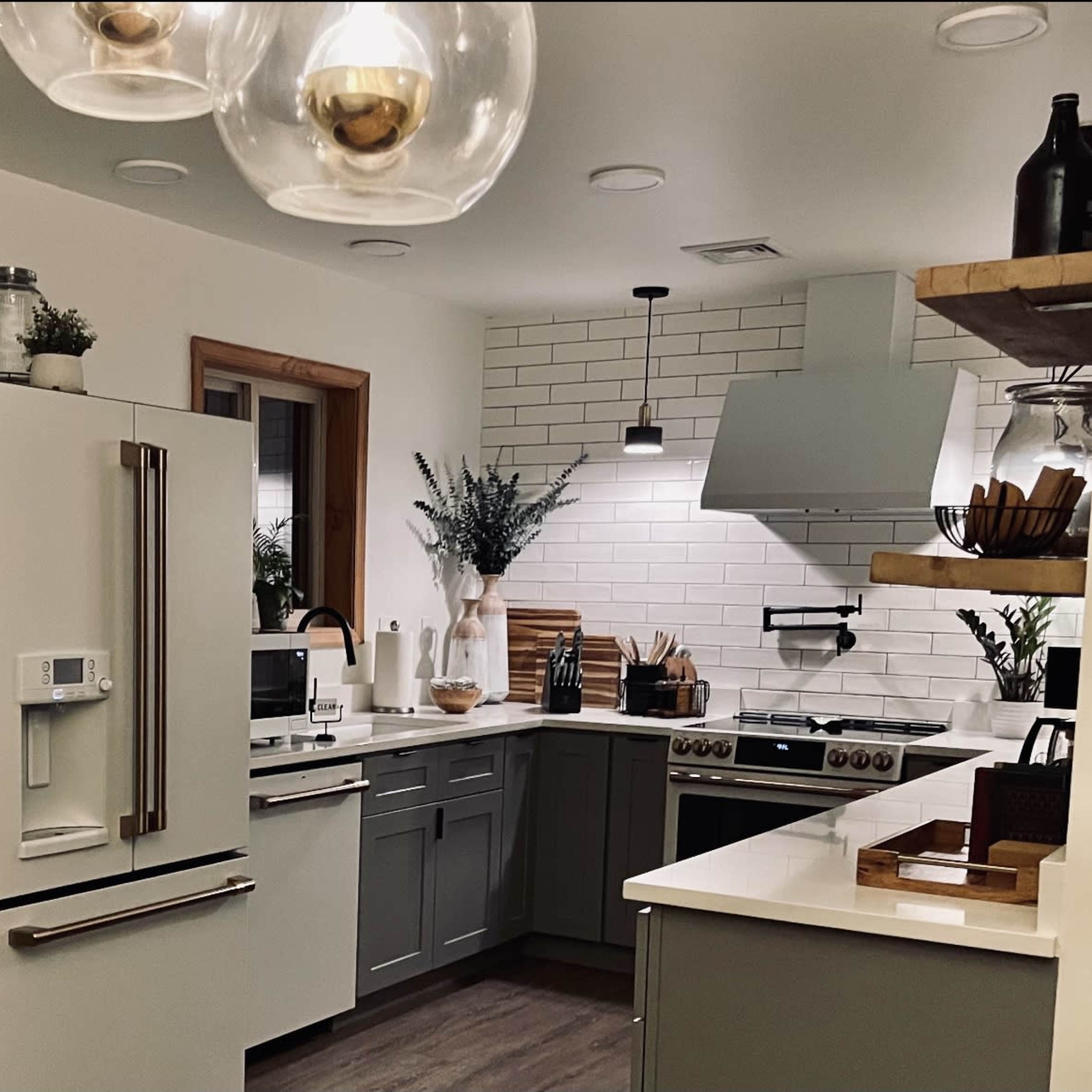 A modern kitchen featuring gray cabinets, a white countertop, stainless steel appliances, and a tile backsplash.