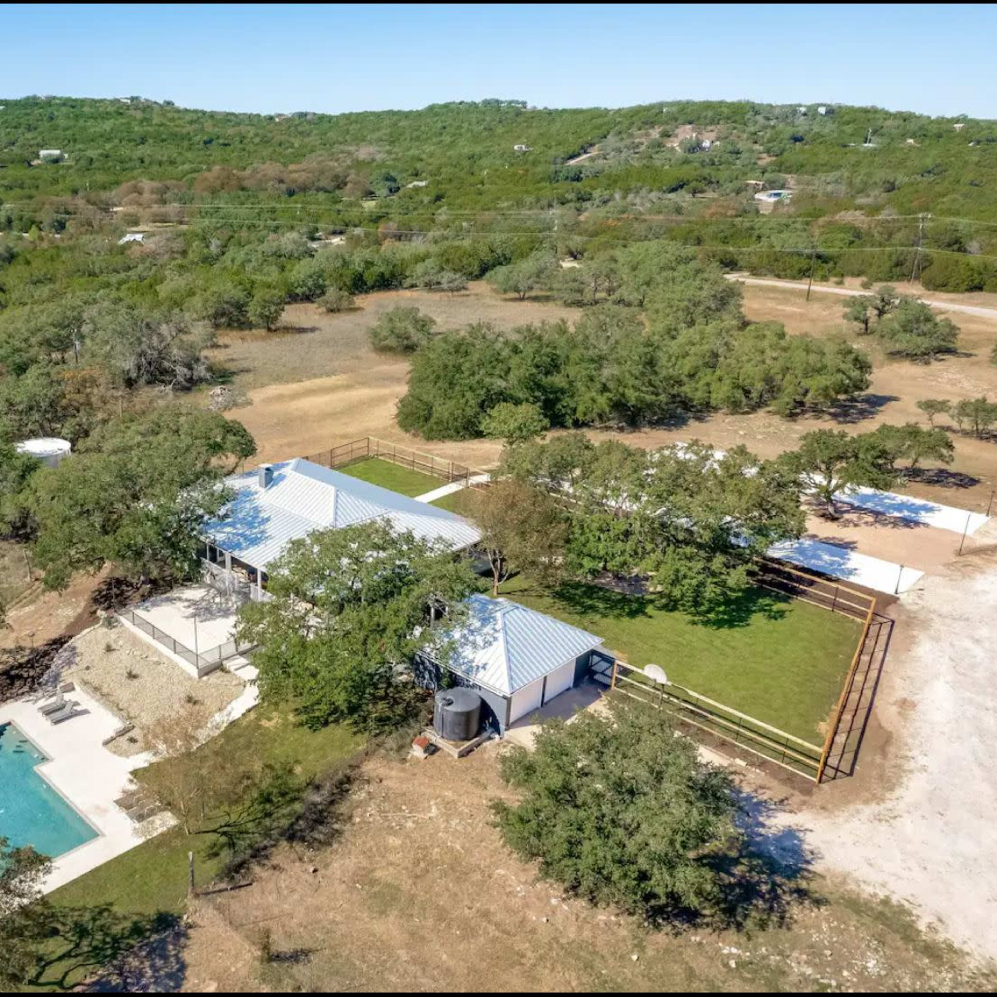 A spacious rural property featuring a house with a pool, surrounded by trees and open land.