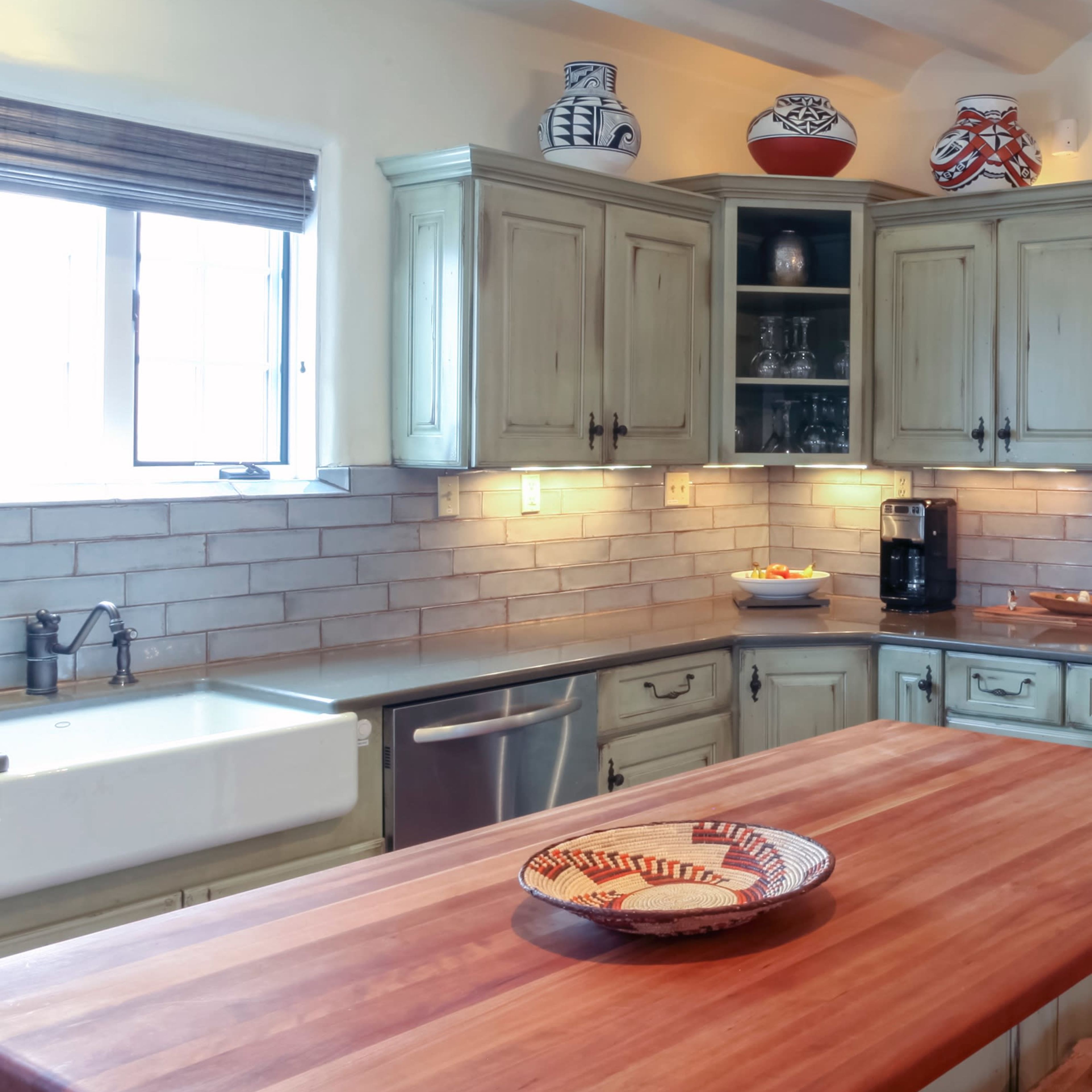 The kitchen features a wooden island with a sink, surrounded by light-colored cabinets and a tiled backsplash.