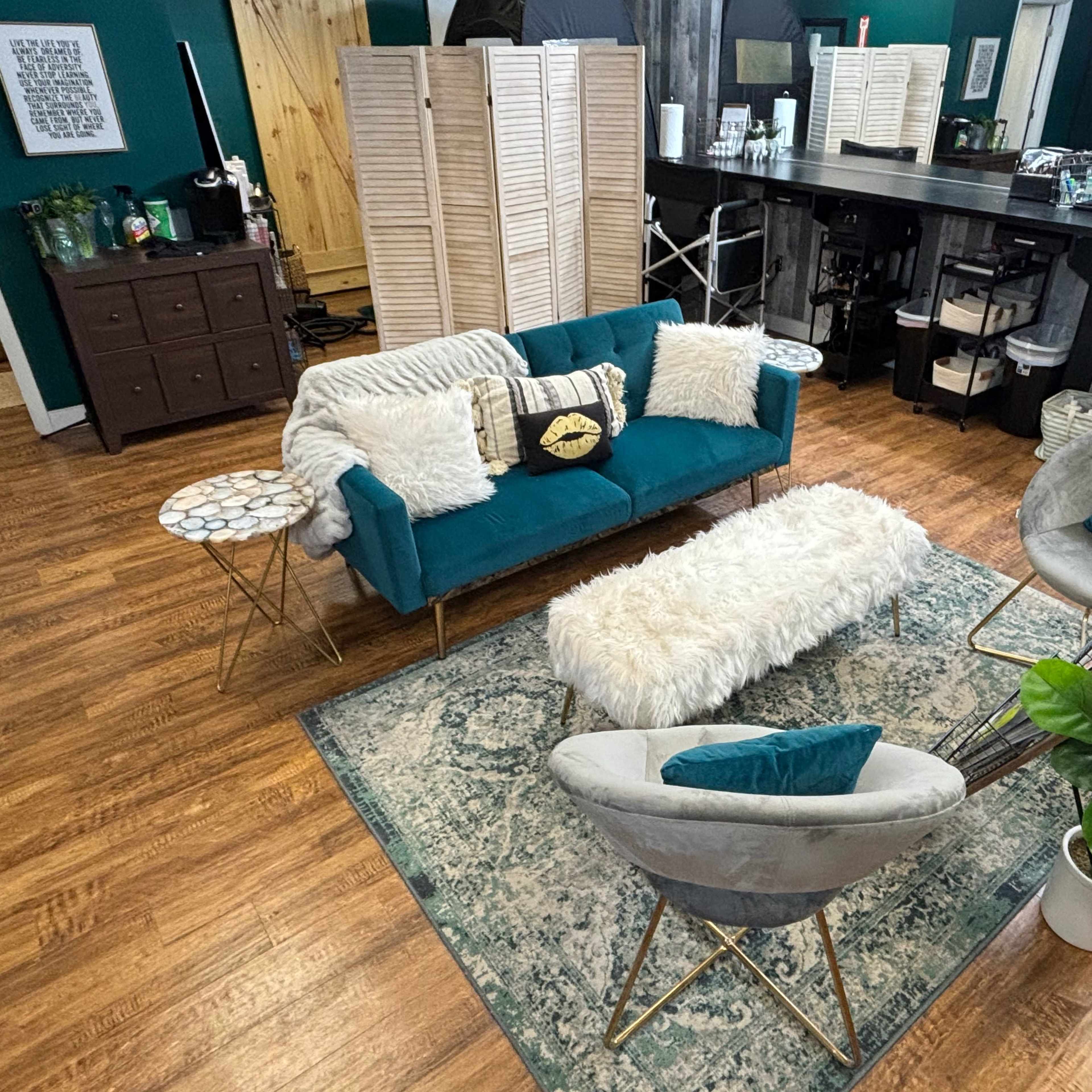 A cozy living space with a teal sofa, two round chairs, a fluffy white coffee table, and a patterned rug on wooden flooring.