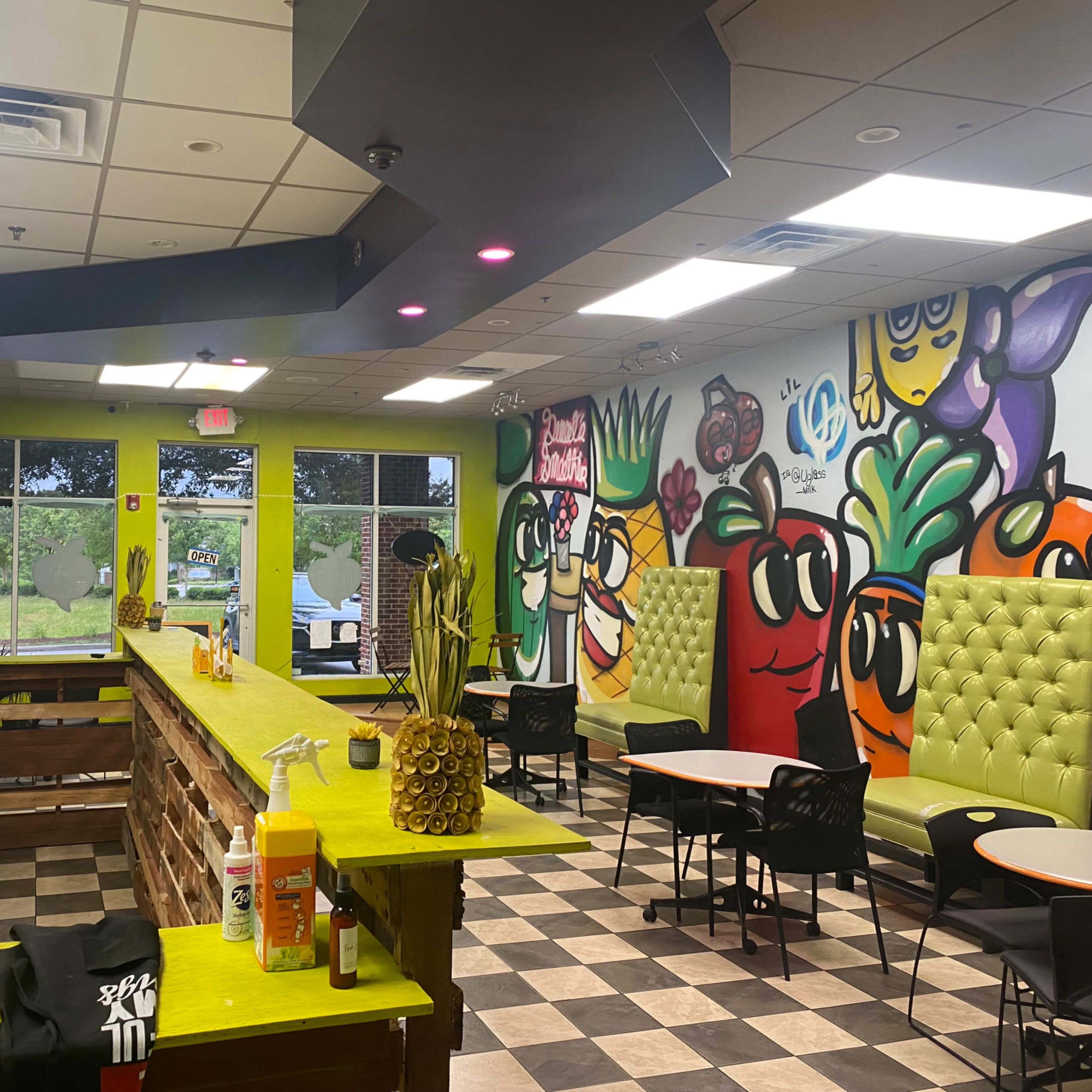 The interior of a vibrant restaurant features colorful murals and green booths with a counter displaying various condiments and drink options.