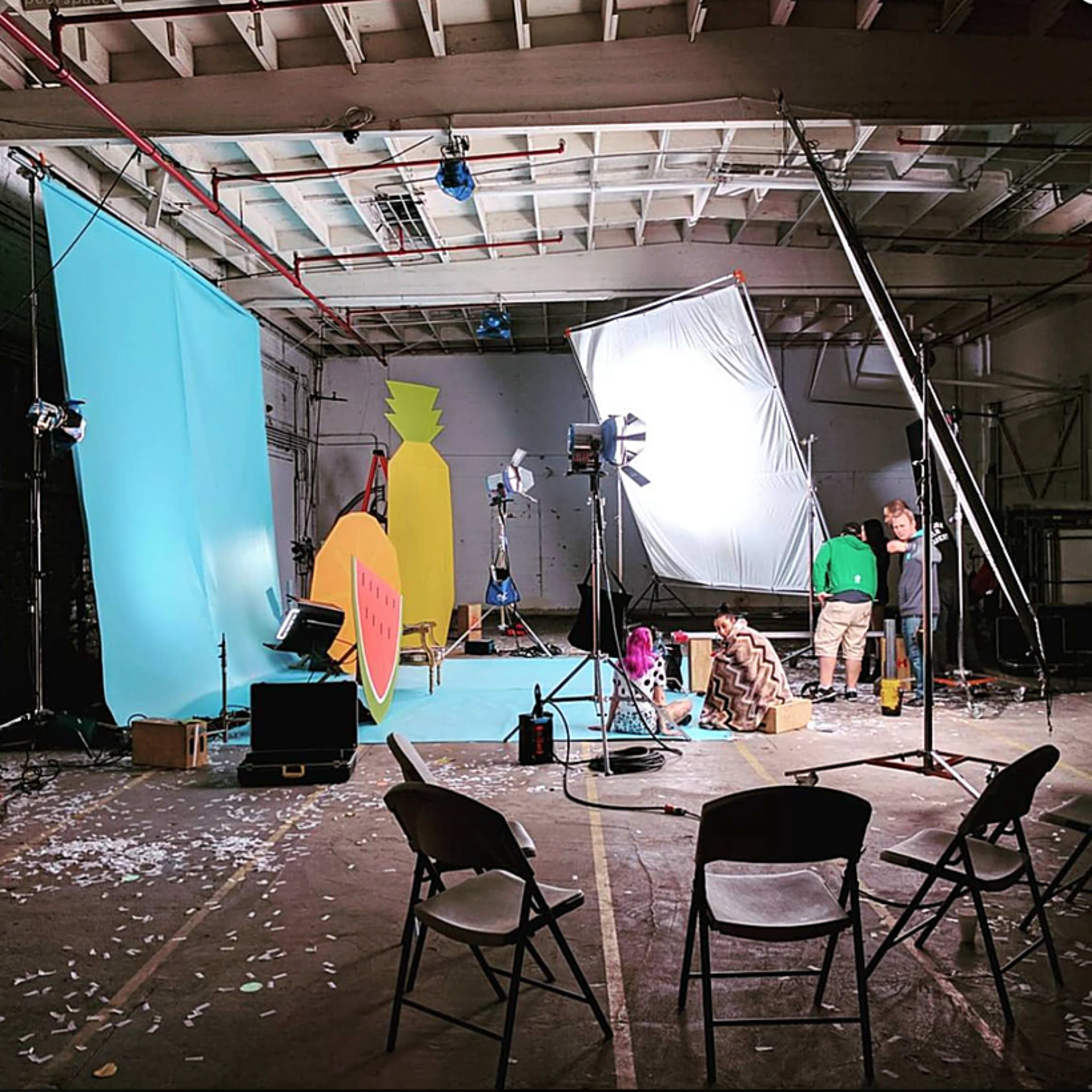 A large, industrial space with vibrant street art on one wall, various scenes of people engaged in creative activities, and contrasting areas featuring urban decay.