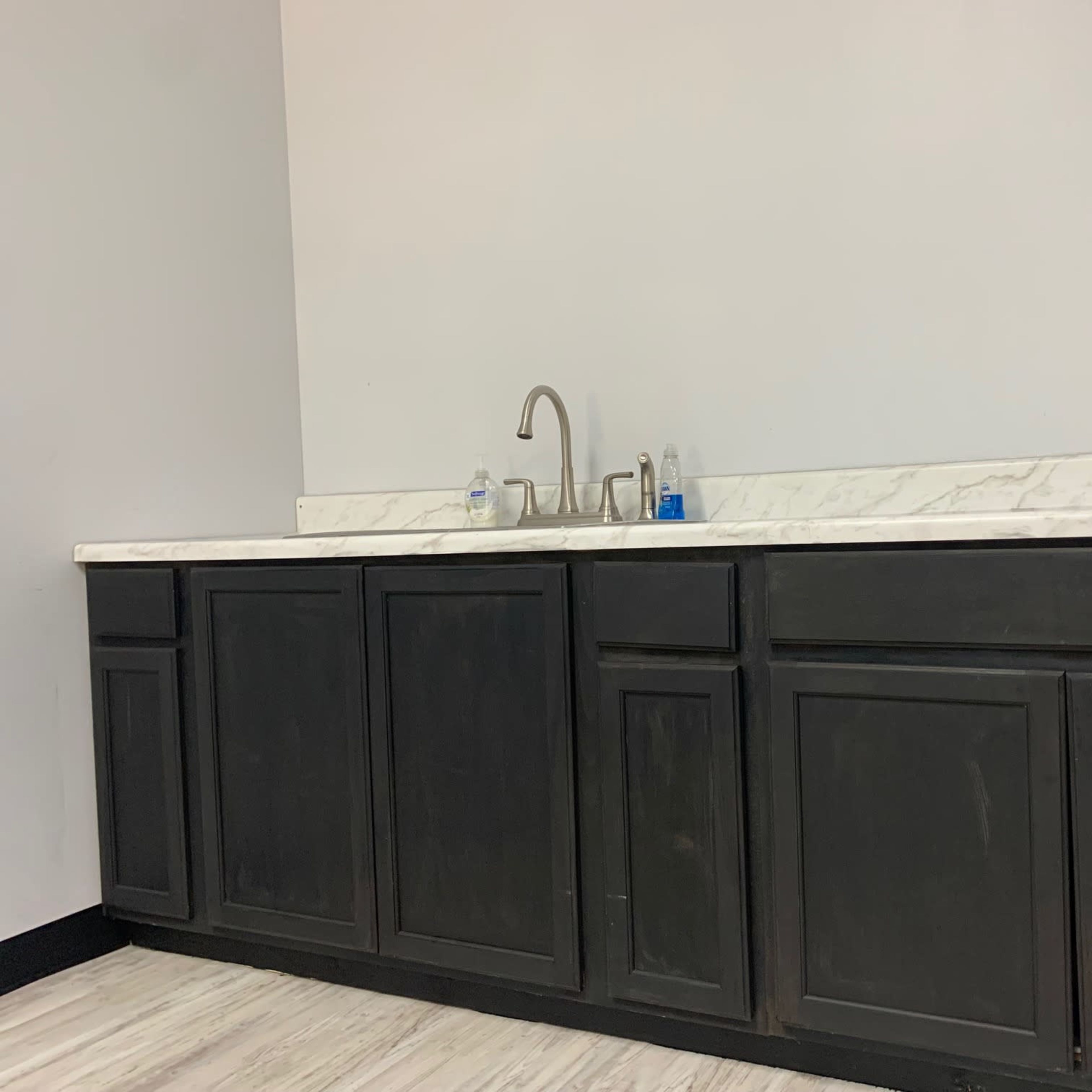 A kitchen area features a marble countertop with a faucet and dark cabinetry beneath.