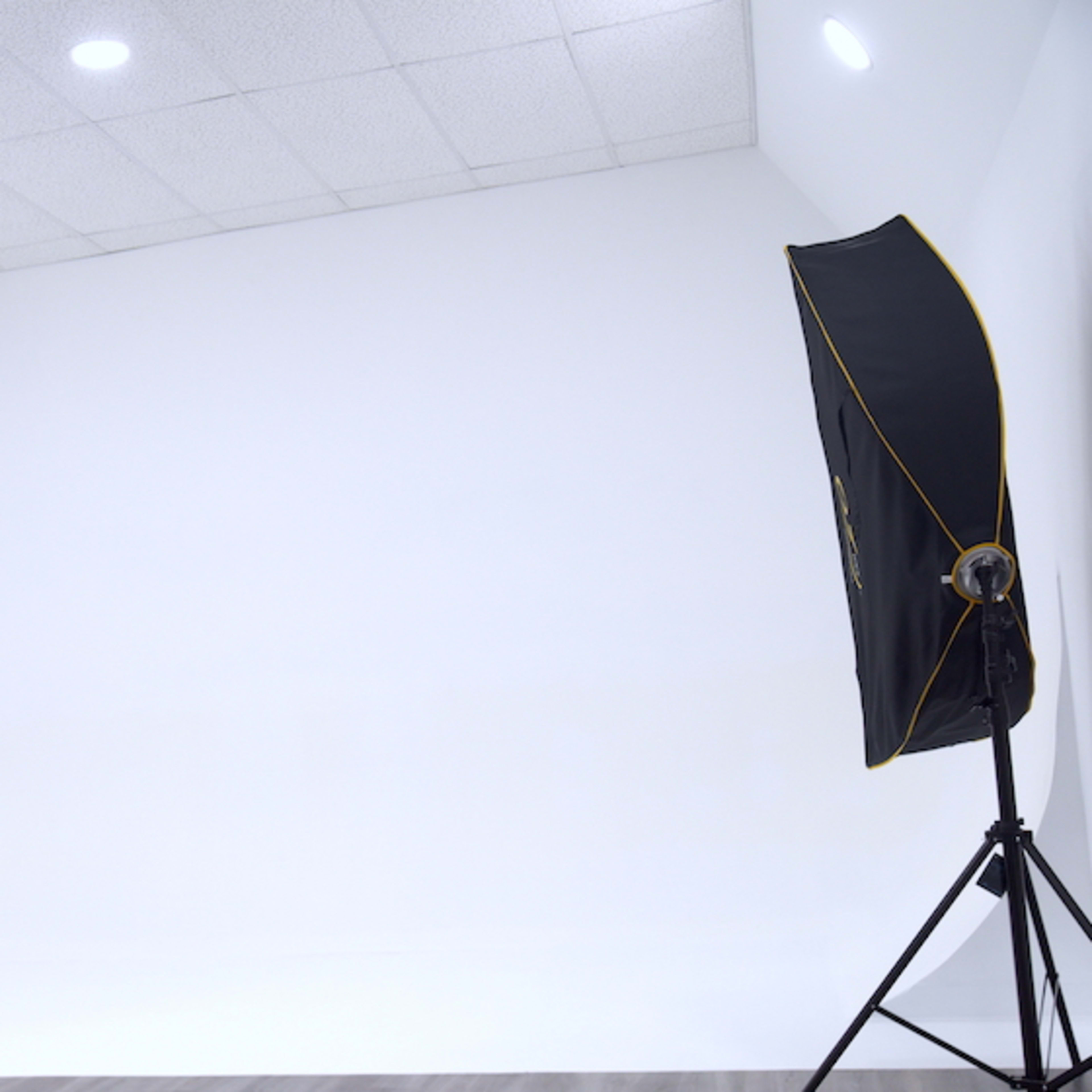 A photography studio features a seamless white backdrop with two softbox lights positioned on either side.