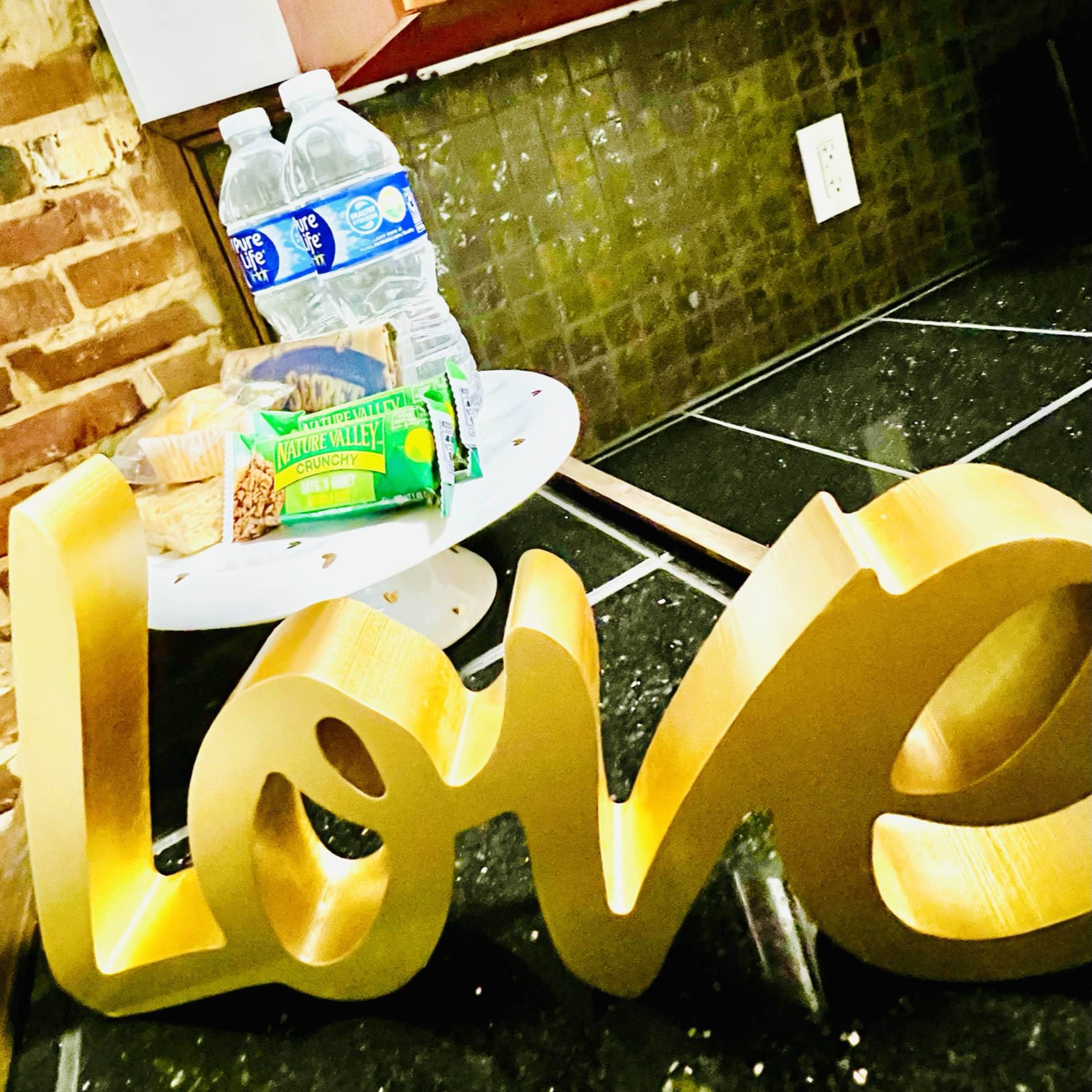 A gold "love" sign is positioned in front of a small table with snacks and bottled water.