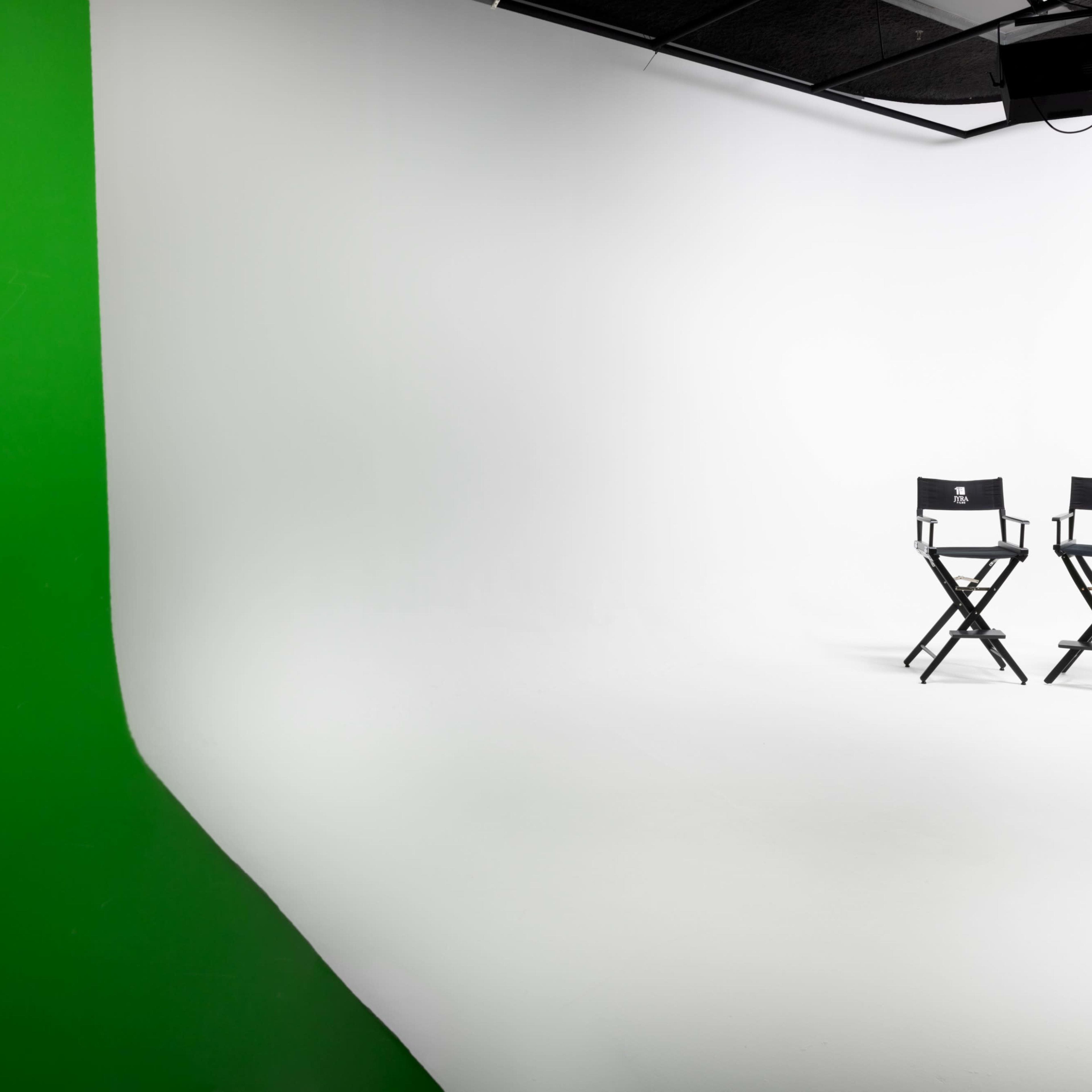 Two black director's chairs positioned on a white backdrop with a green screen on one side.