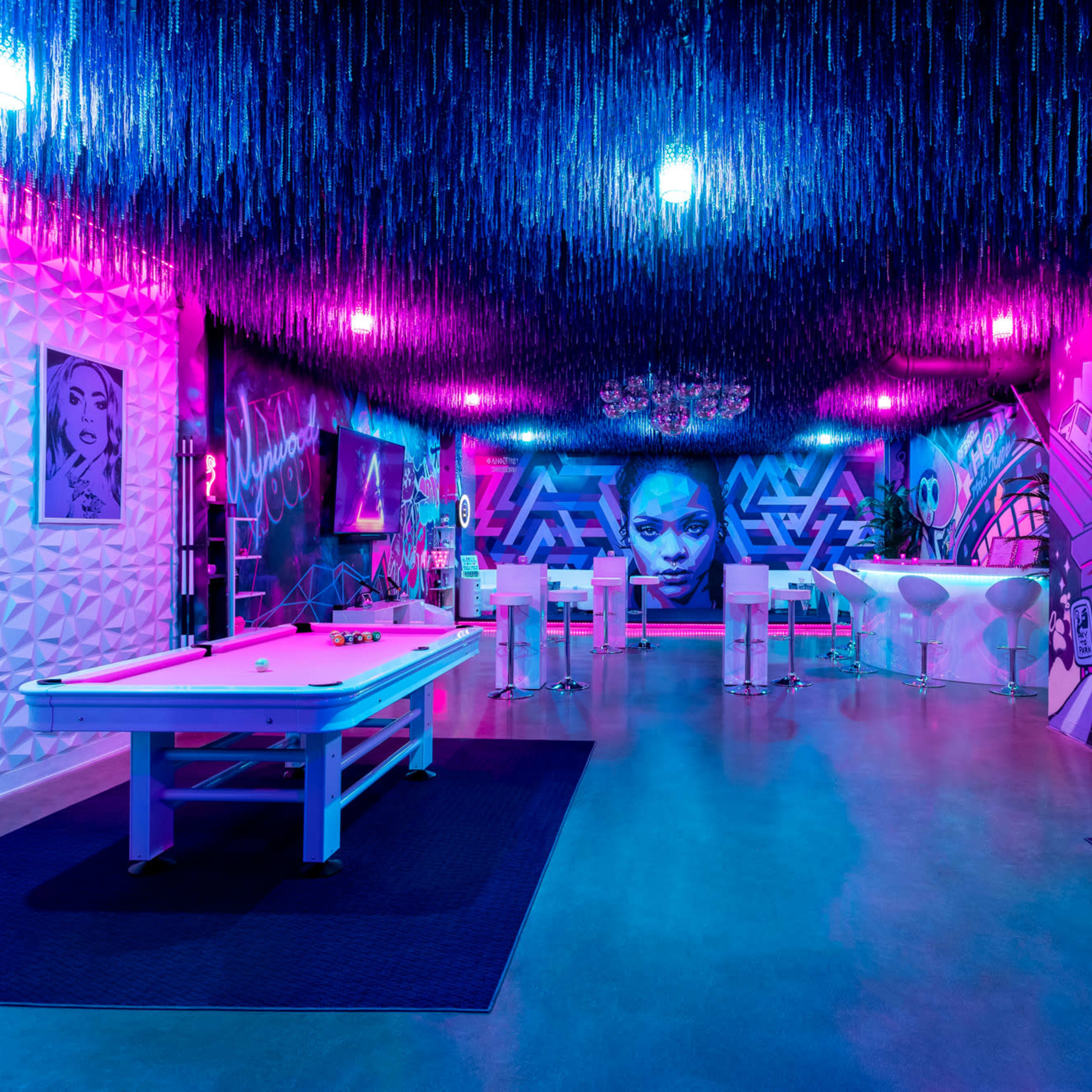 The scene depicts a vibrant, neon-lit lounge with colorful murals, a pool table, and modern furniture.