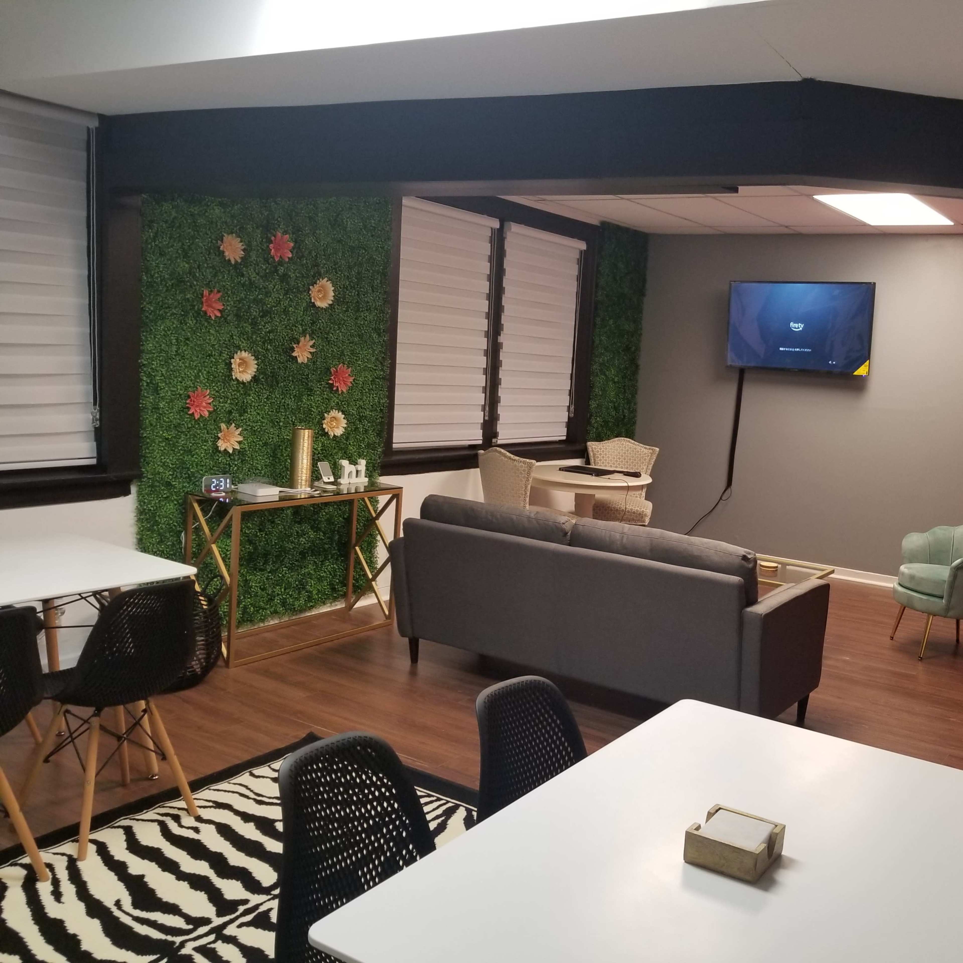 A modern room featuring green and floral accent walls, a television on one side, and a seating area with a couch and chairs.