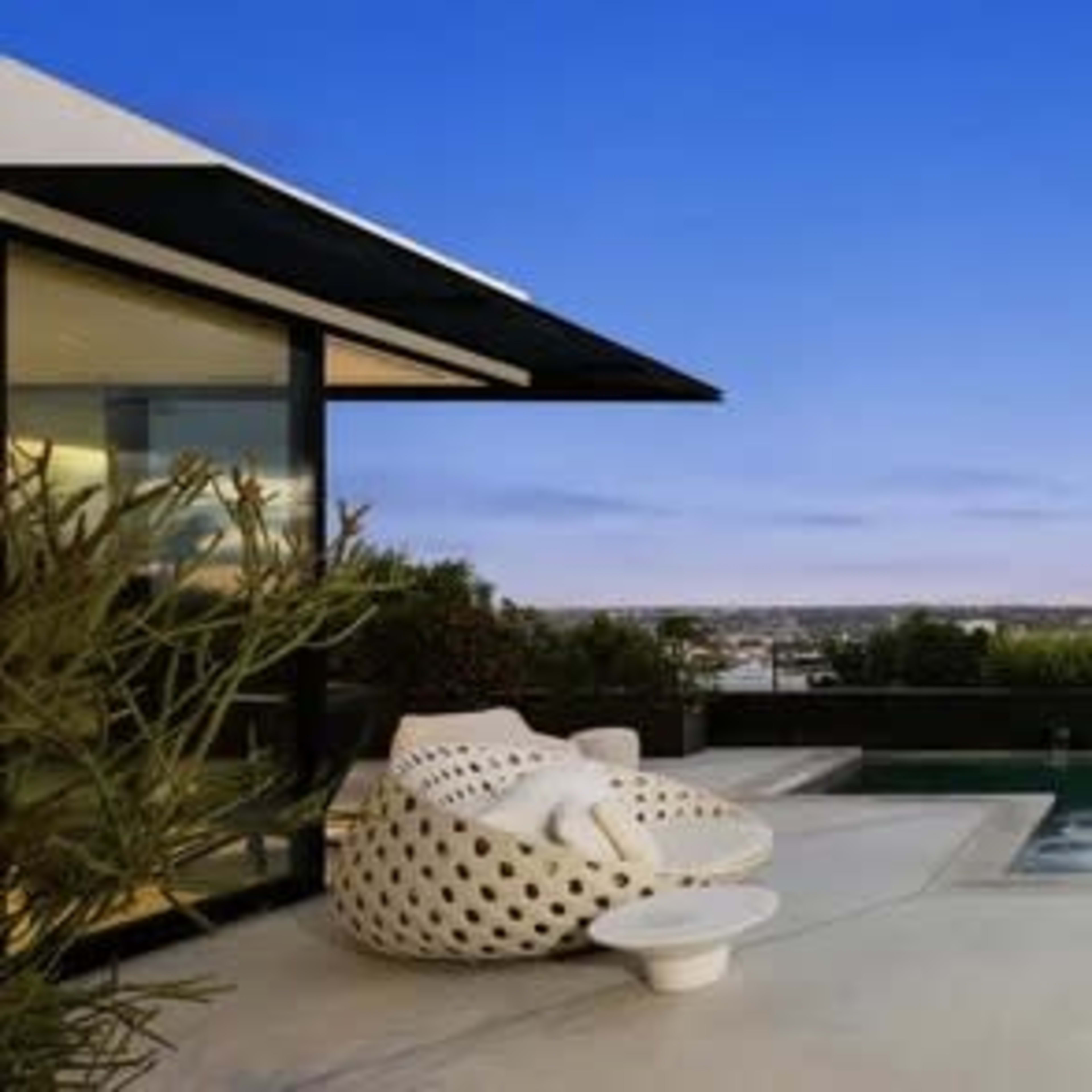 A modern outdoor space features a pool surrounded by sleek architecture and outdoor seating against a twilight sky.
