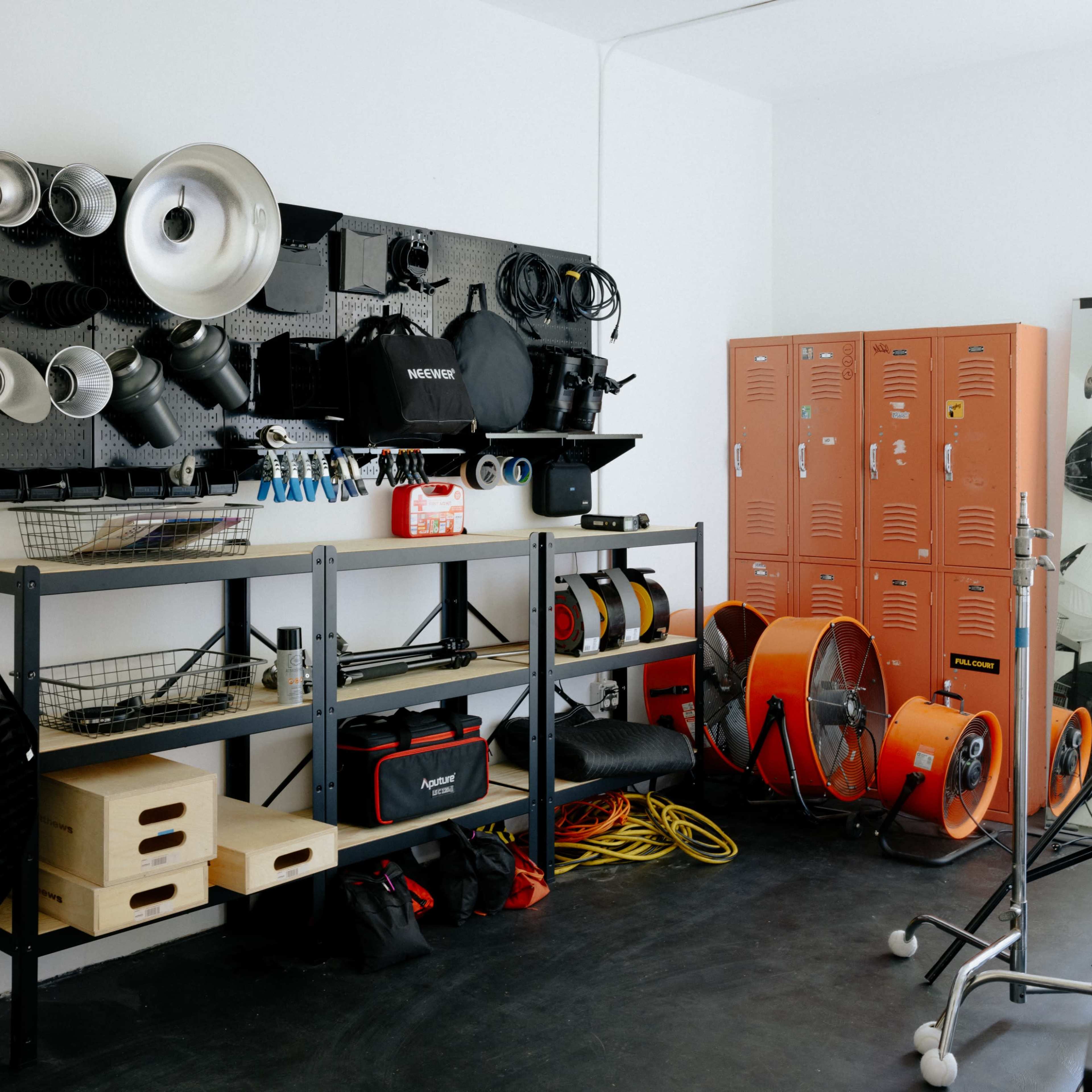 A workspace contains shelves with photography equipment and storage lockers, along with various tools and cables arranged neatly on the floor.