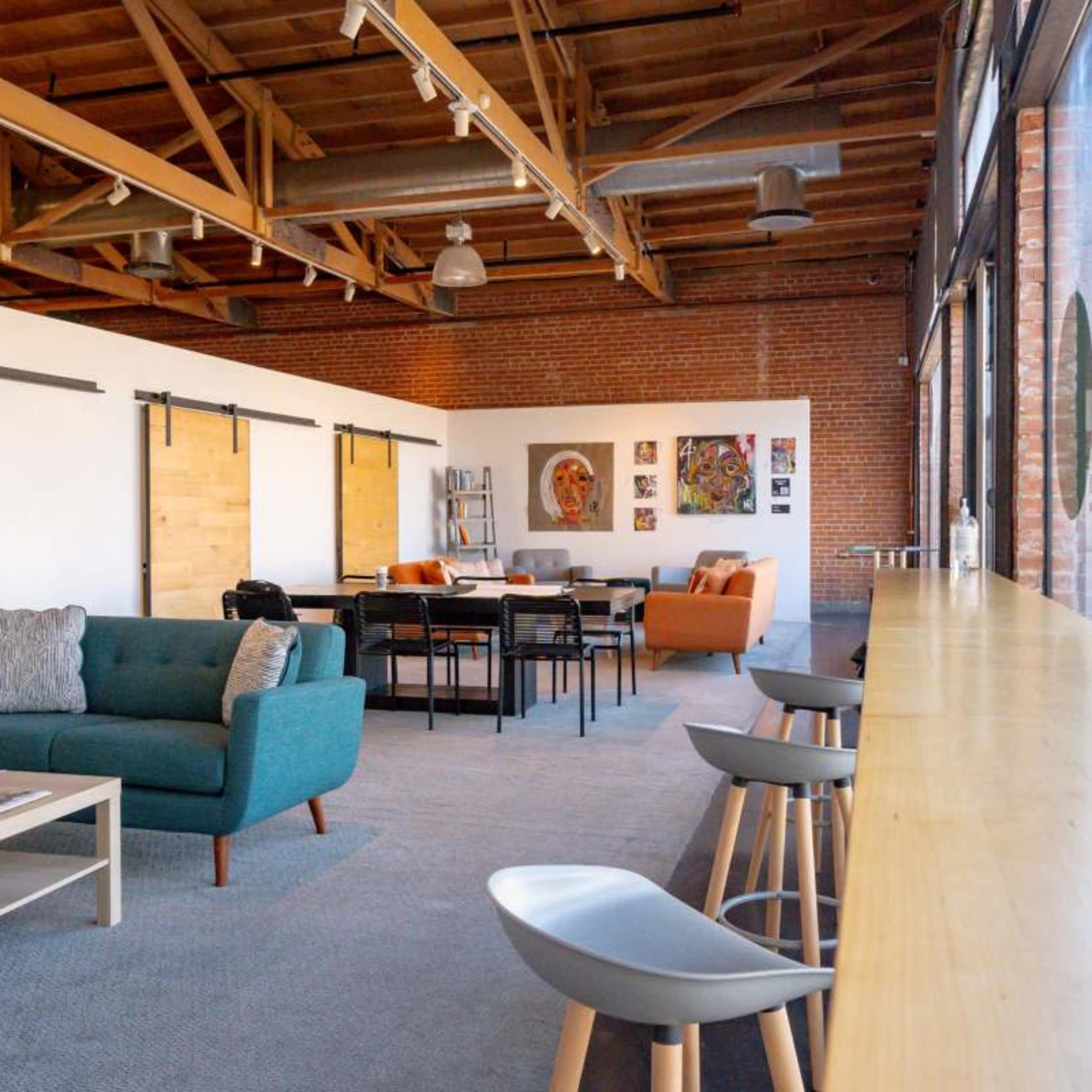 A spacious interior with a seating area featuring a blue couch, a wood table, and large windows that provide natural light.