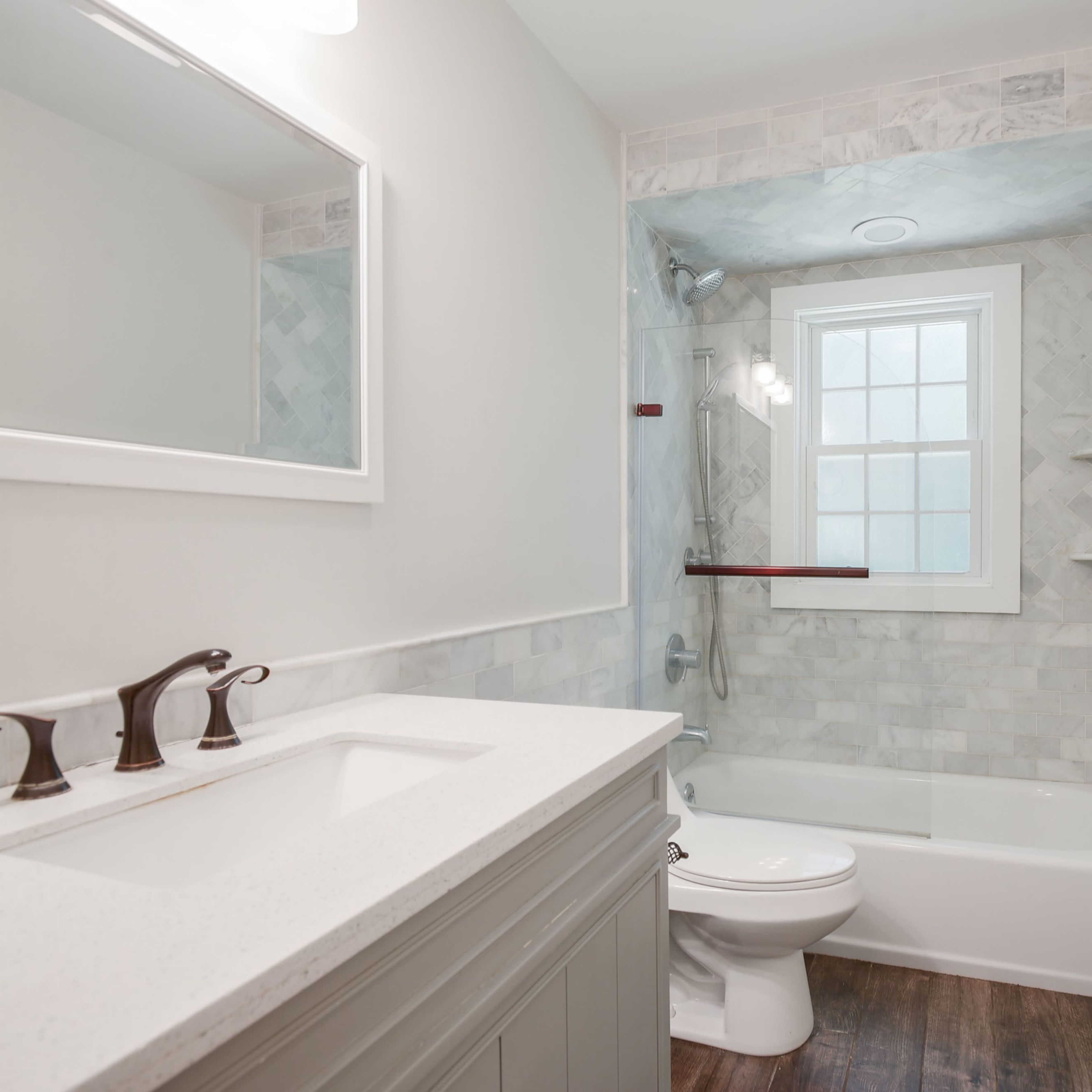The bathroom features a tiled shower area, a bathtub, a sink with a vanity, and a window.