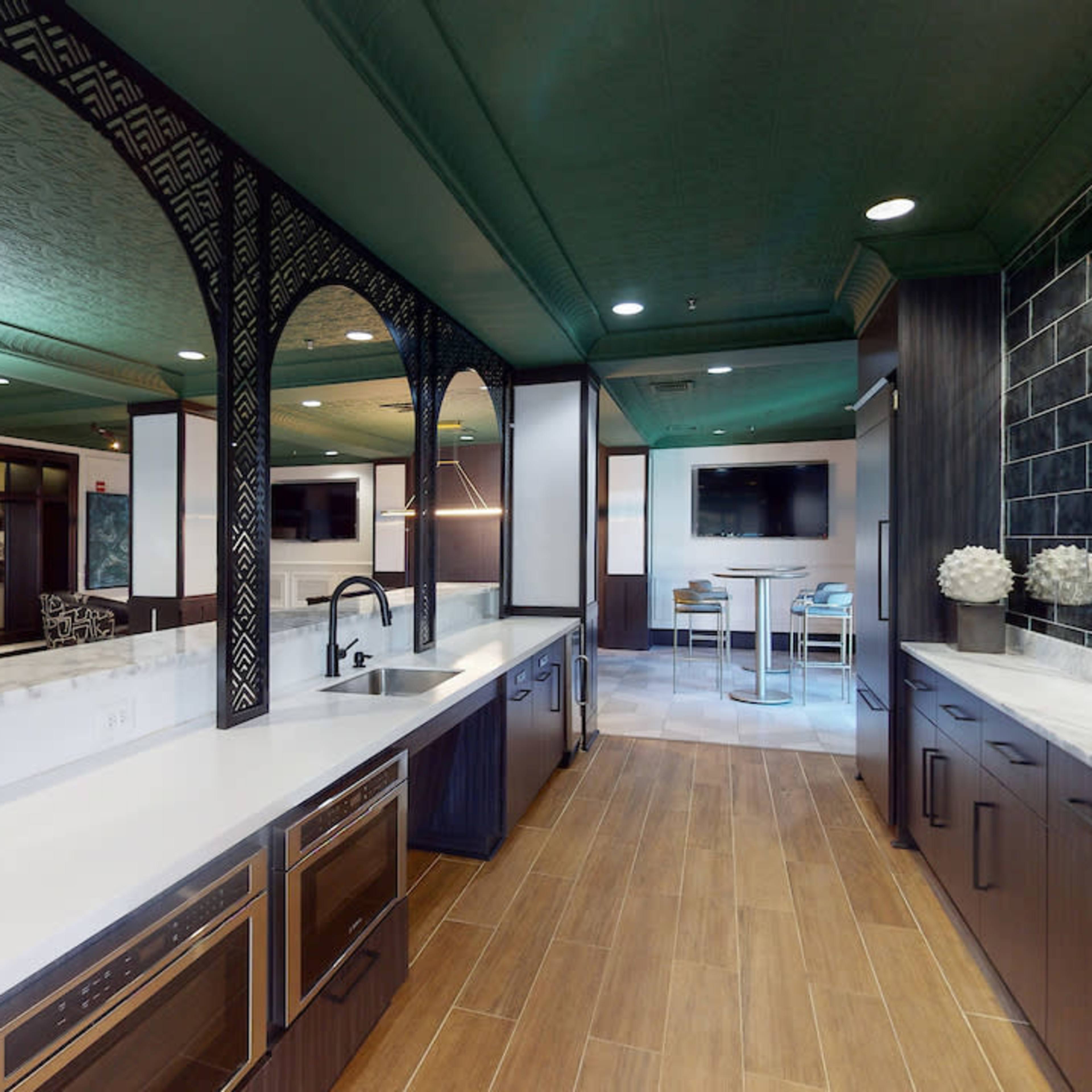 A modern kitchen with dark cabinetry, a white countertop, and decorative archways.
