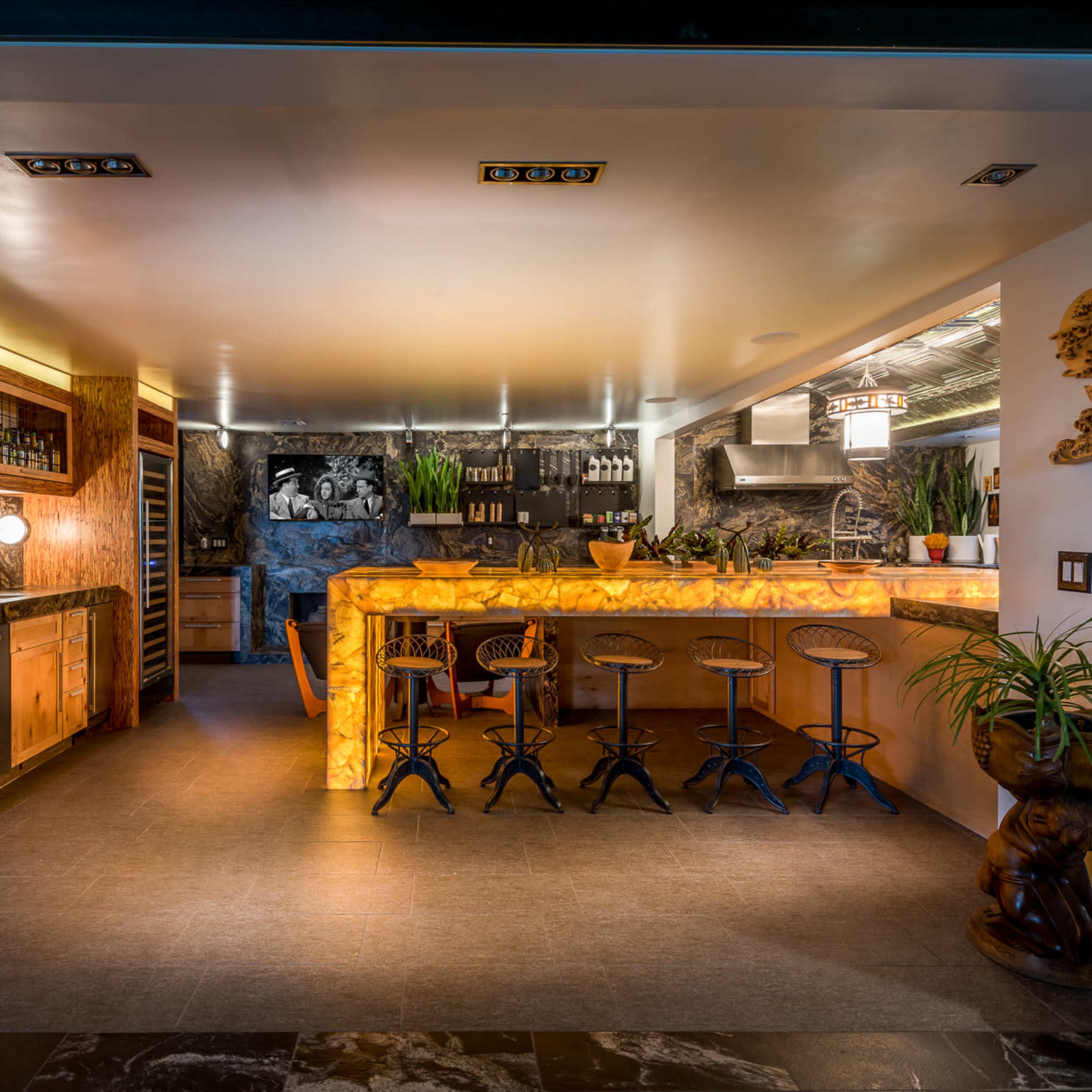 A modern kitchen and bar area with wooden cabinetry, a large, curved bar counter, and a seating arrangement with high stools.
