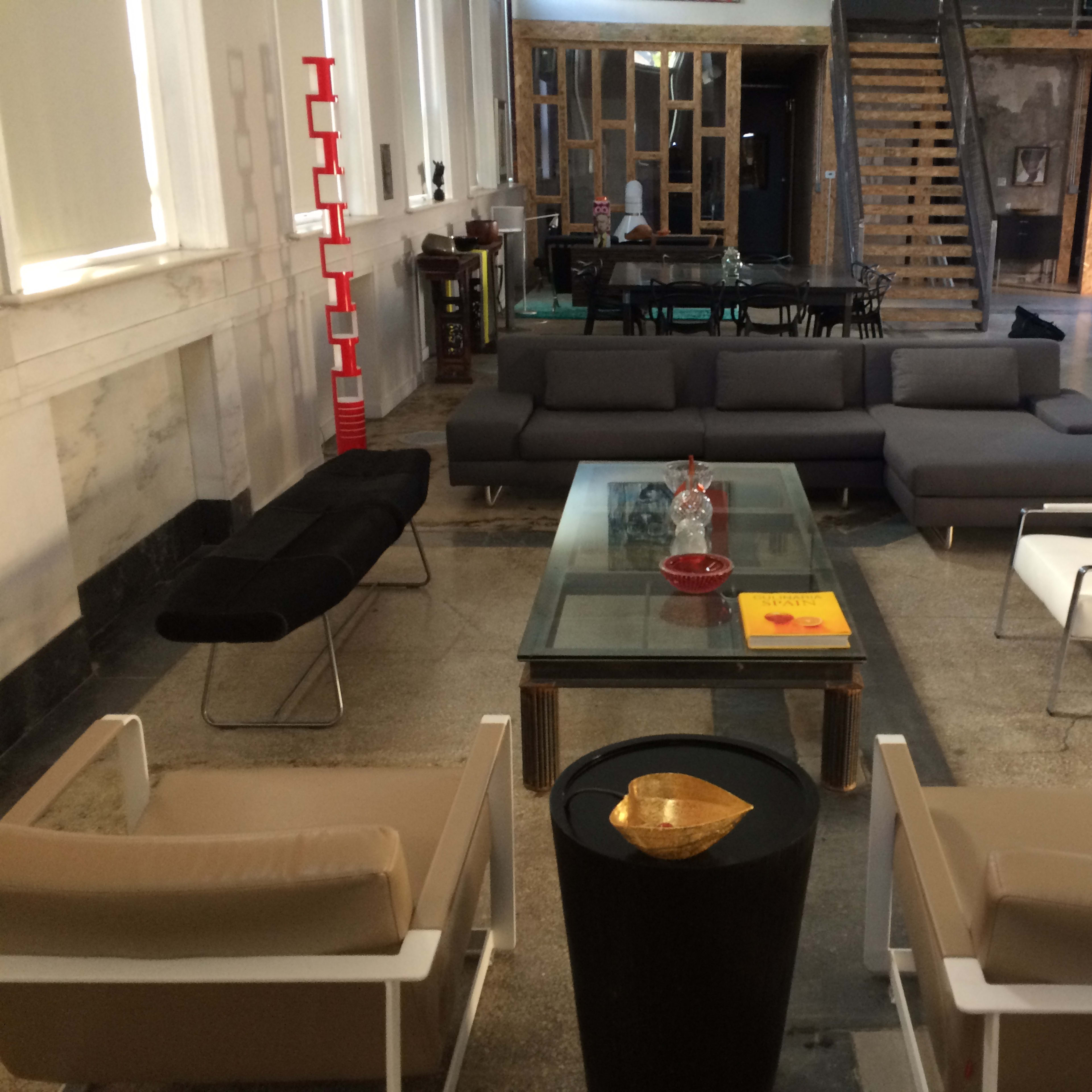 A spacious interior with modern seating arrangements, a glass coffee table, and a staircase leading to an upper level.