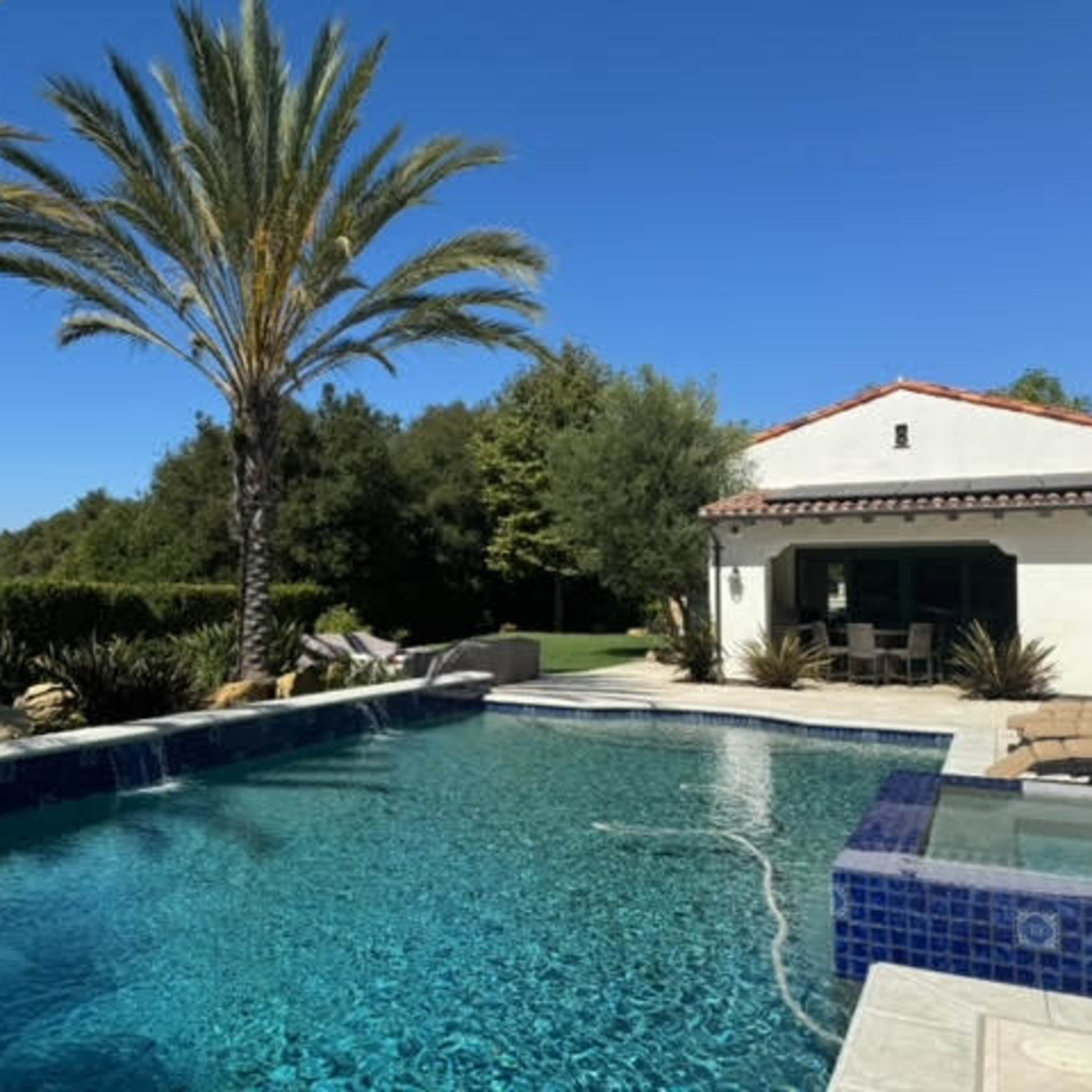 Mediterranean outdoor space with separate garden courtyard and backyard with a pool and spa.  It is surrounded by palm trees, olive trees, fruit trees, cypress trees.  Expansive and open back yard with endless views! Image in Turtle Rock, Irvine, CA