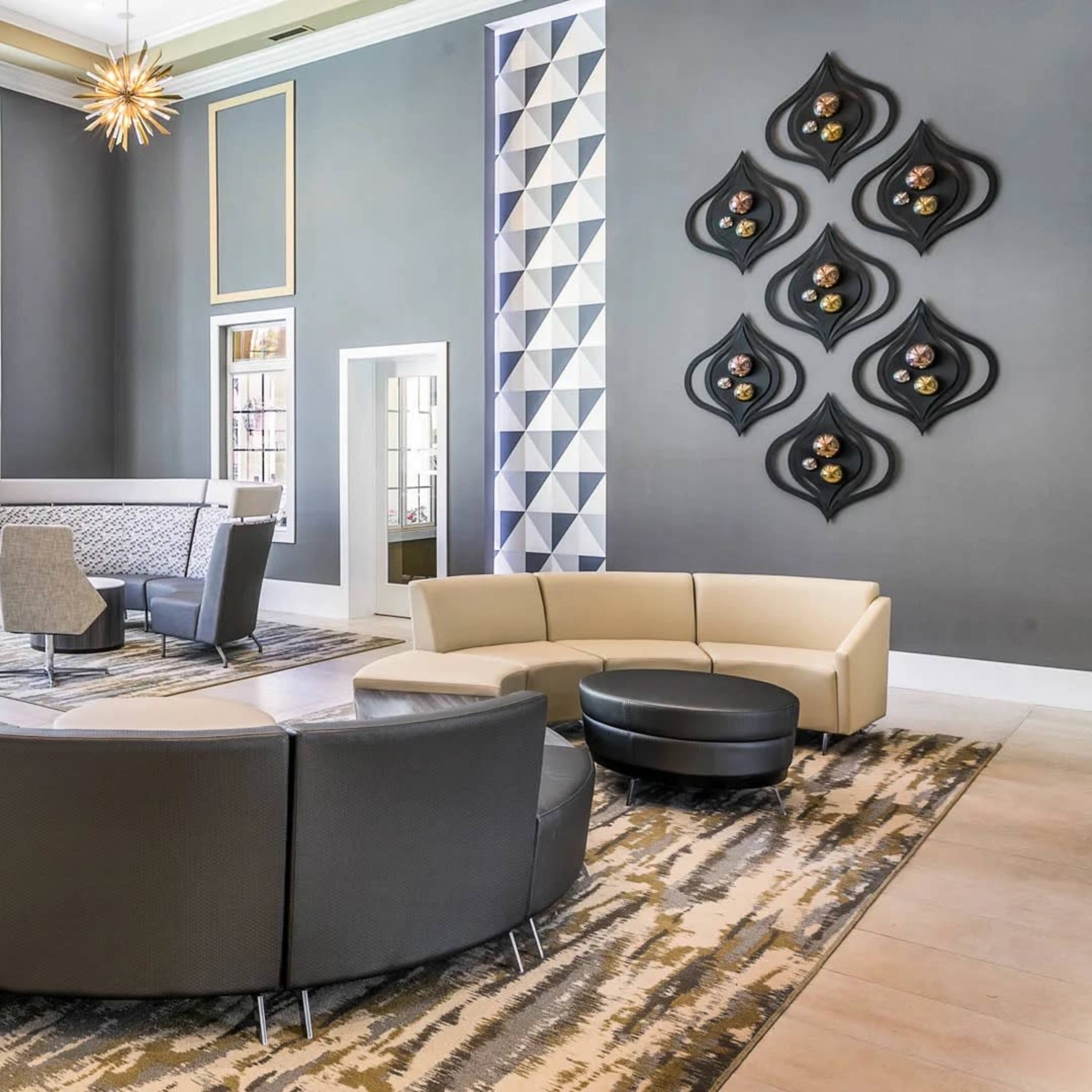 A modern lobby area featuring a circular seating arrangement, a large window with natural light, and decorative wall art.