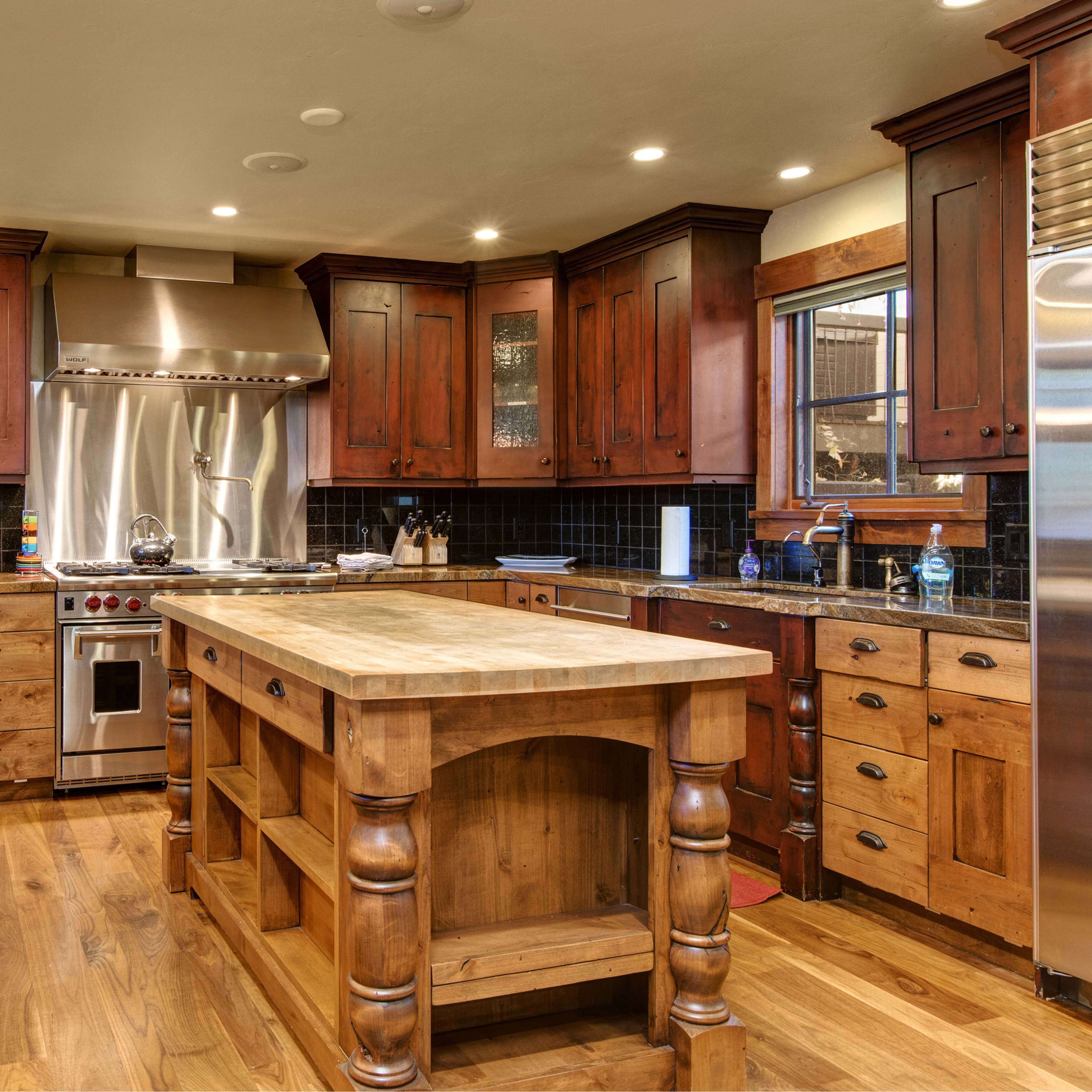 A spacious kitchen with wooden cabinetry, stainless steel appliances, and a central island made of wood.