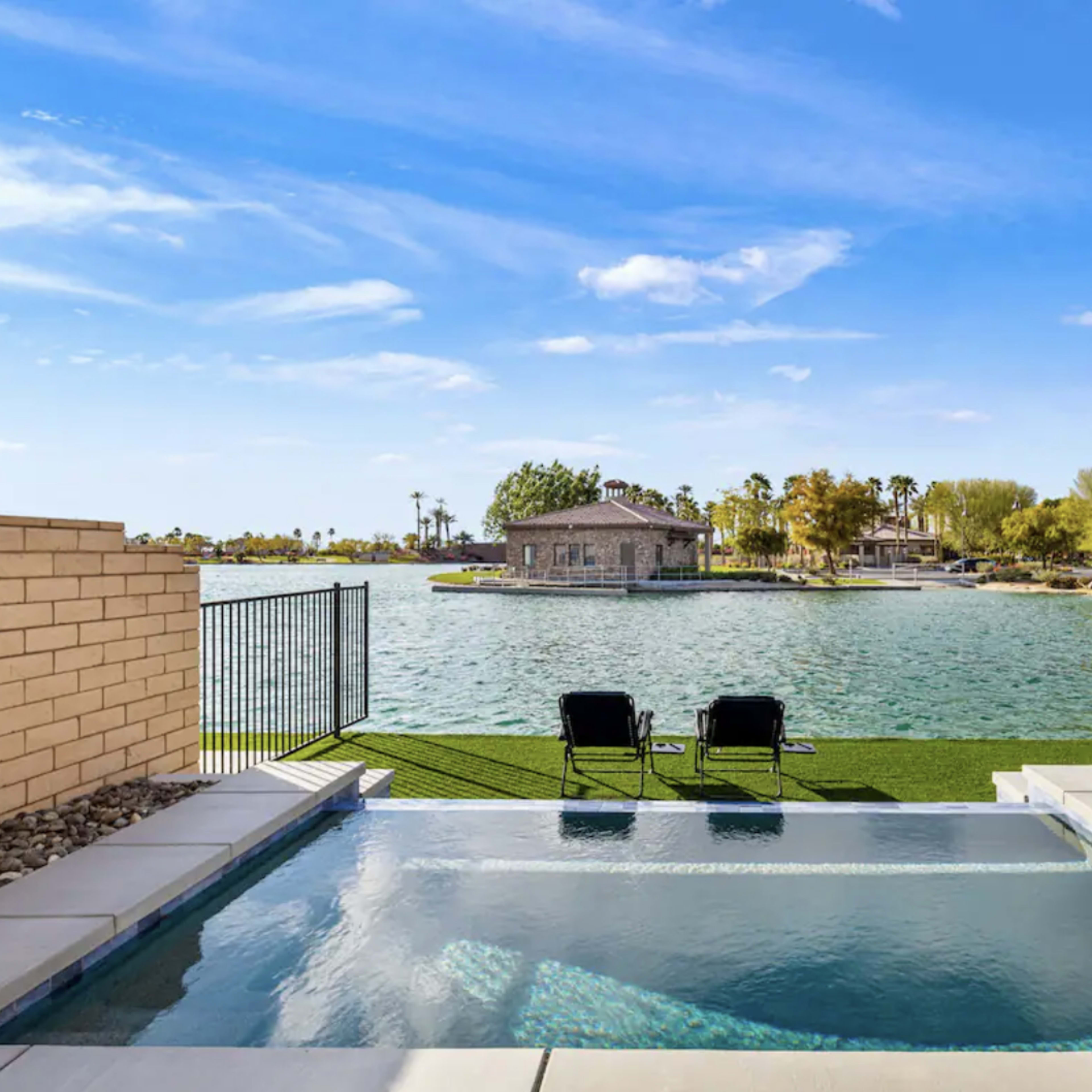 A swimming pool overlooking a lake with a small house on an island in the background.