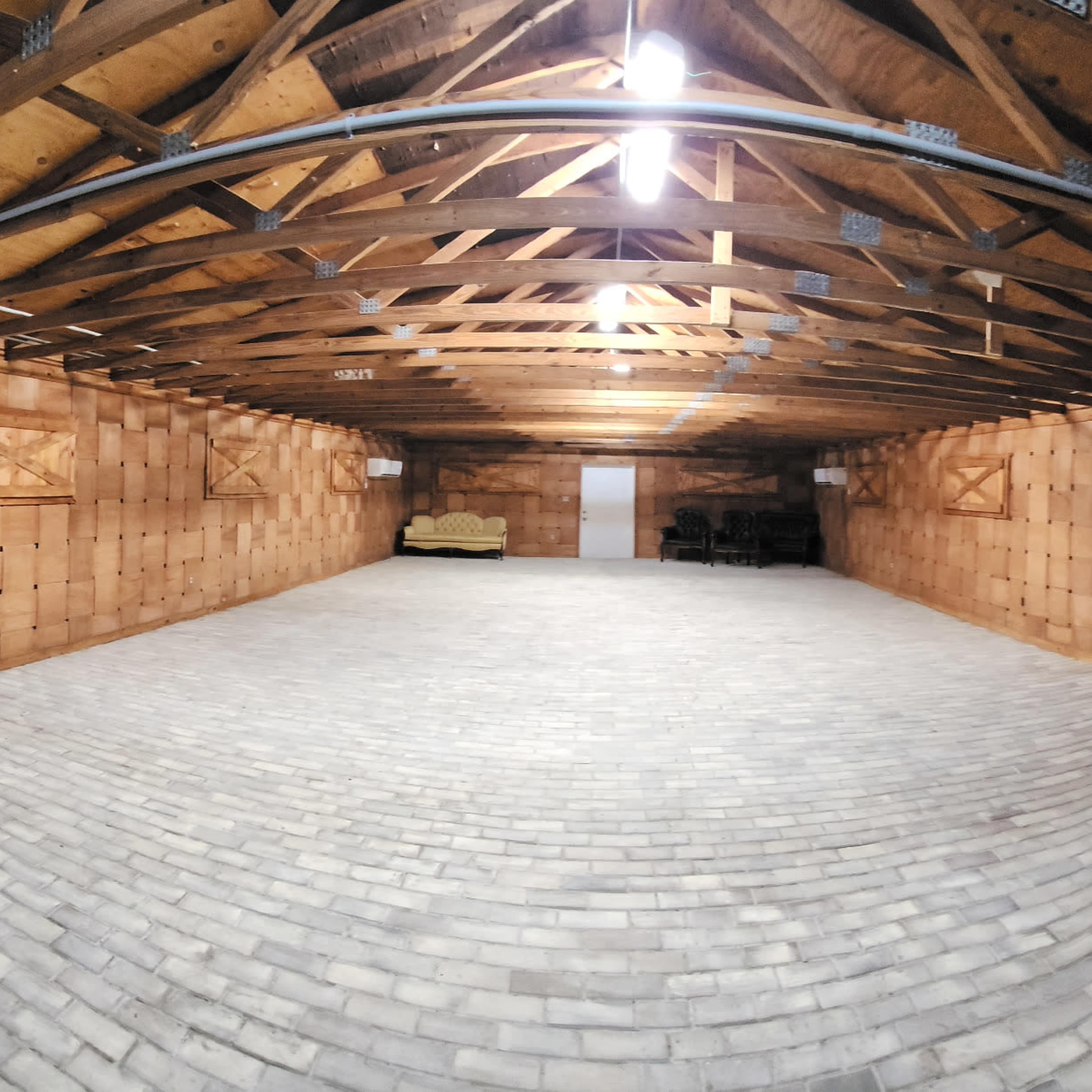 A spacious basement with a flat stone floor, wooden walls, and exposed beams in the ceiling.