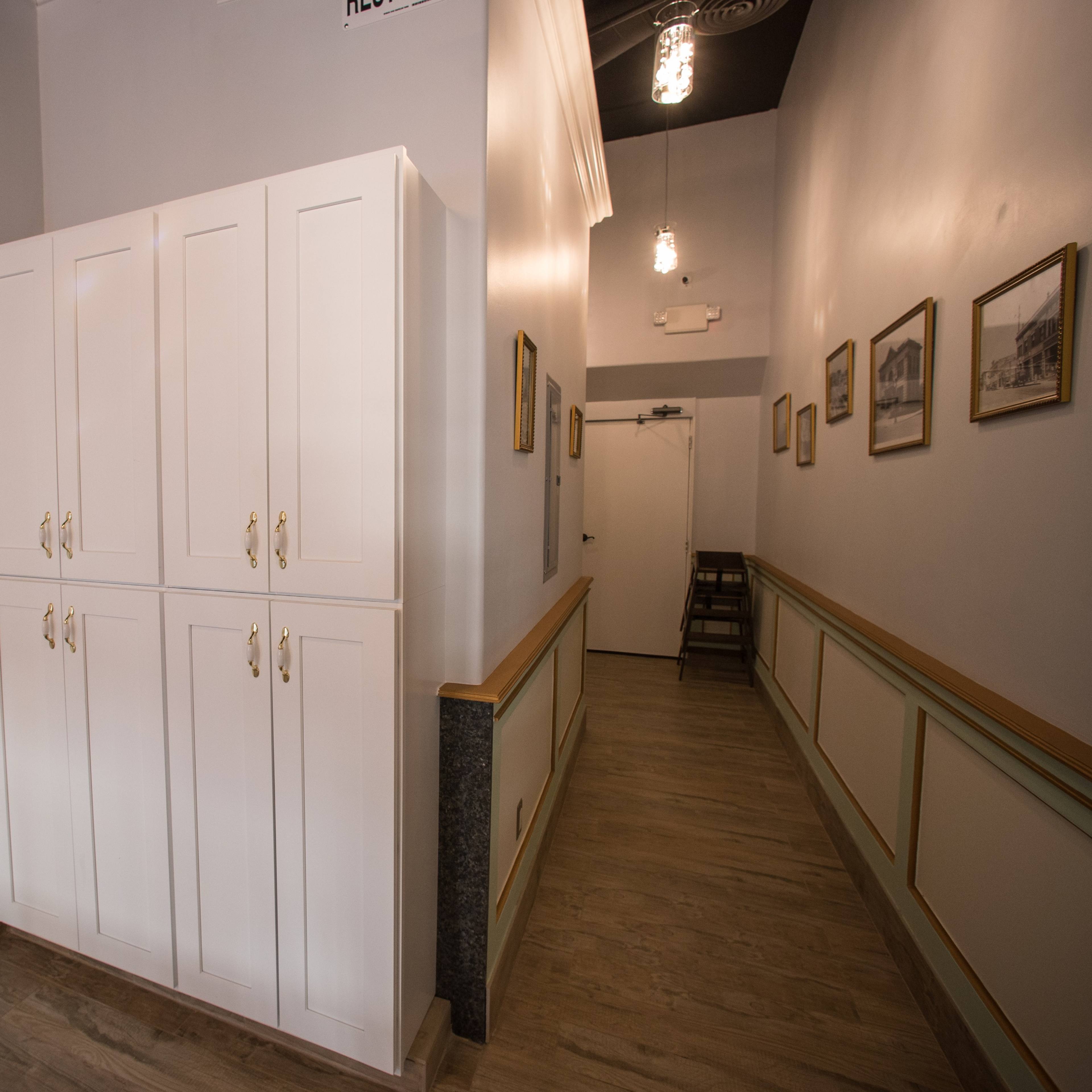 A hallway features a white cabinet on the left and framed pictures on the walls.