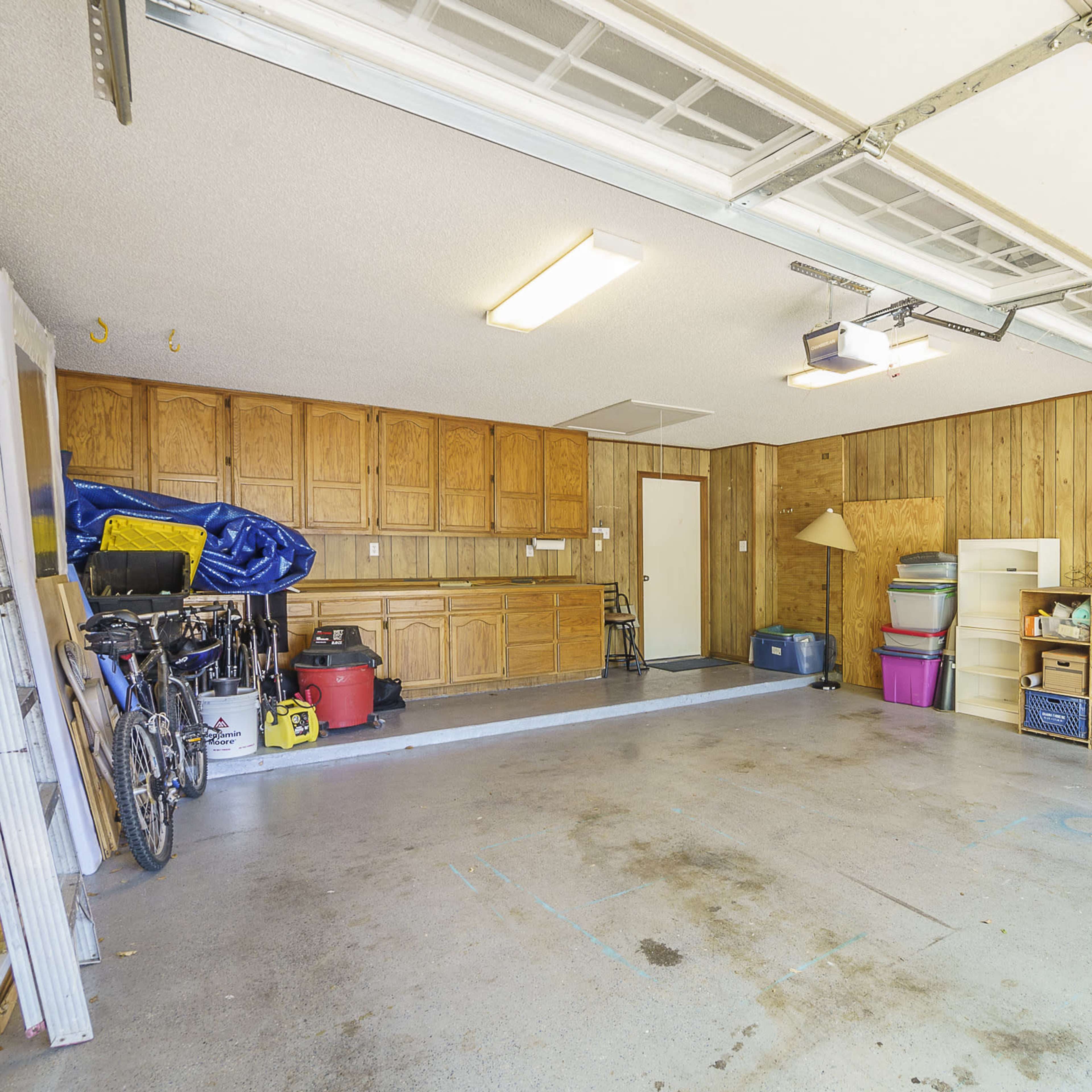 A spacious garage with wooden paneling, shelves filled with storage containers, and some bicycles parked along the wall.