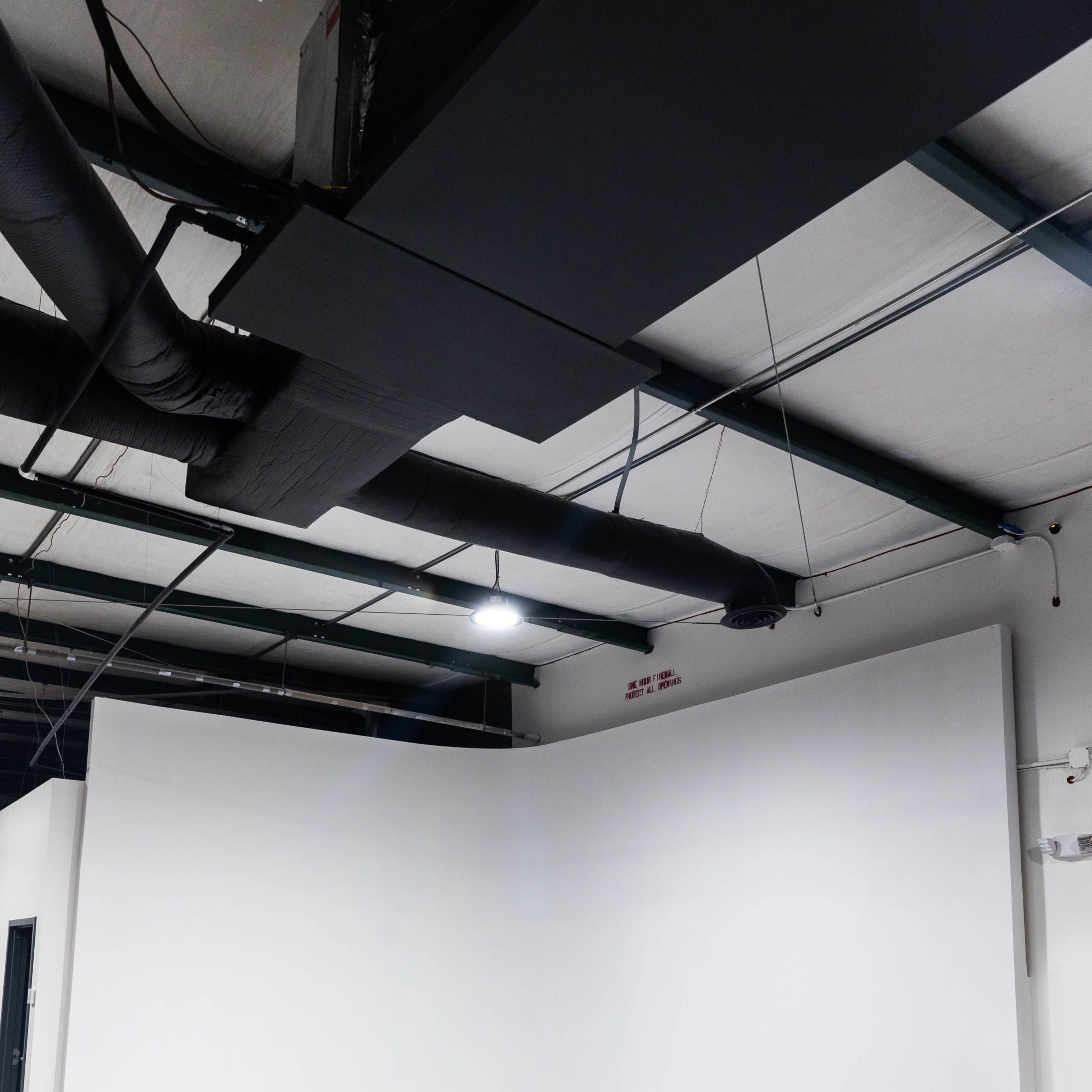A spacious photography studio with a large white cyclorama wall and exposed ceilings.