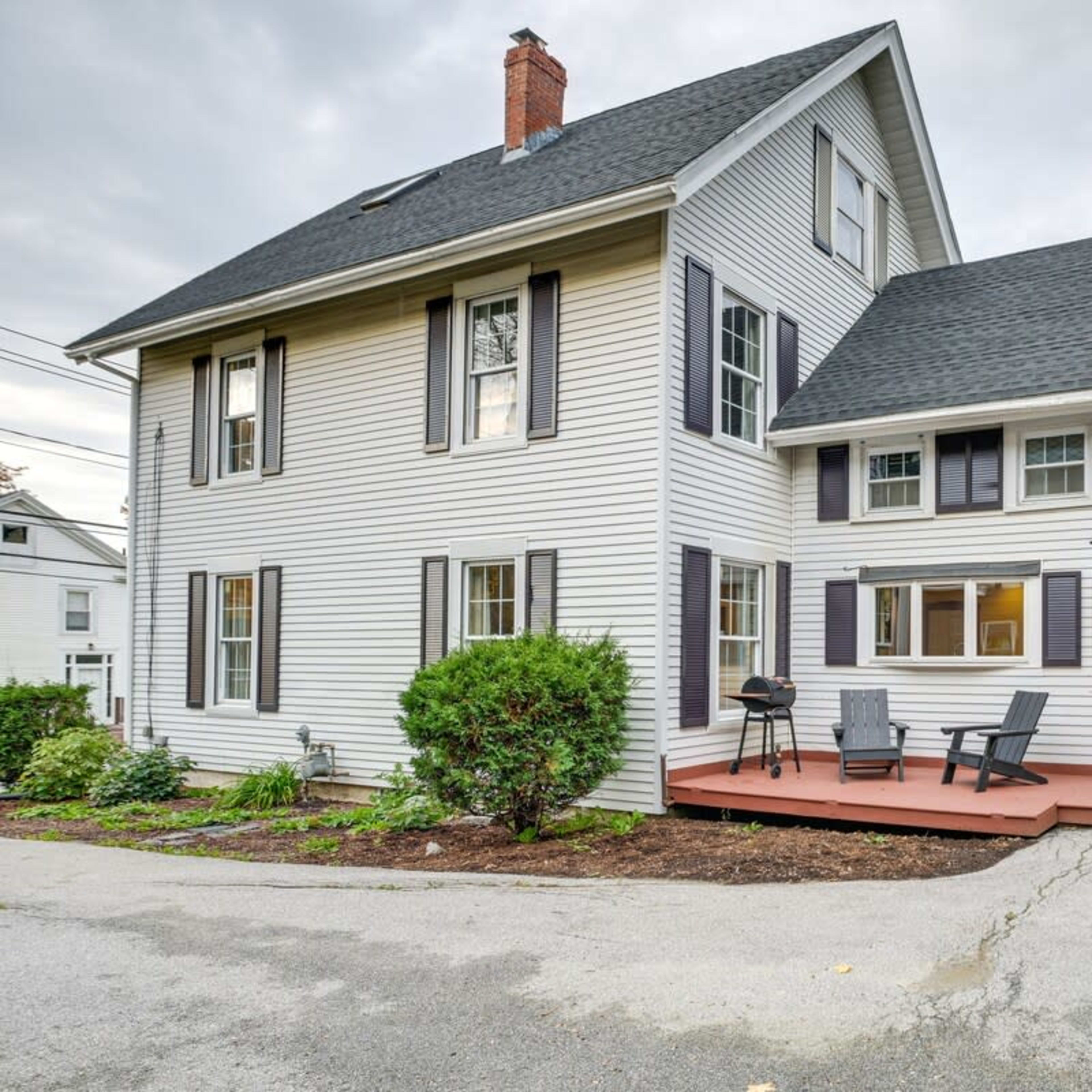 A two-story house with white siding, black shutters, and a wooden porch is visible in the image.