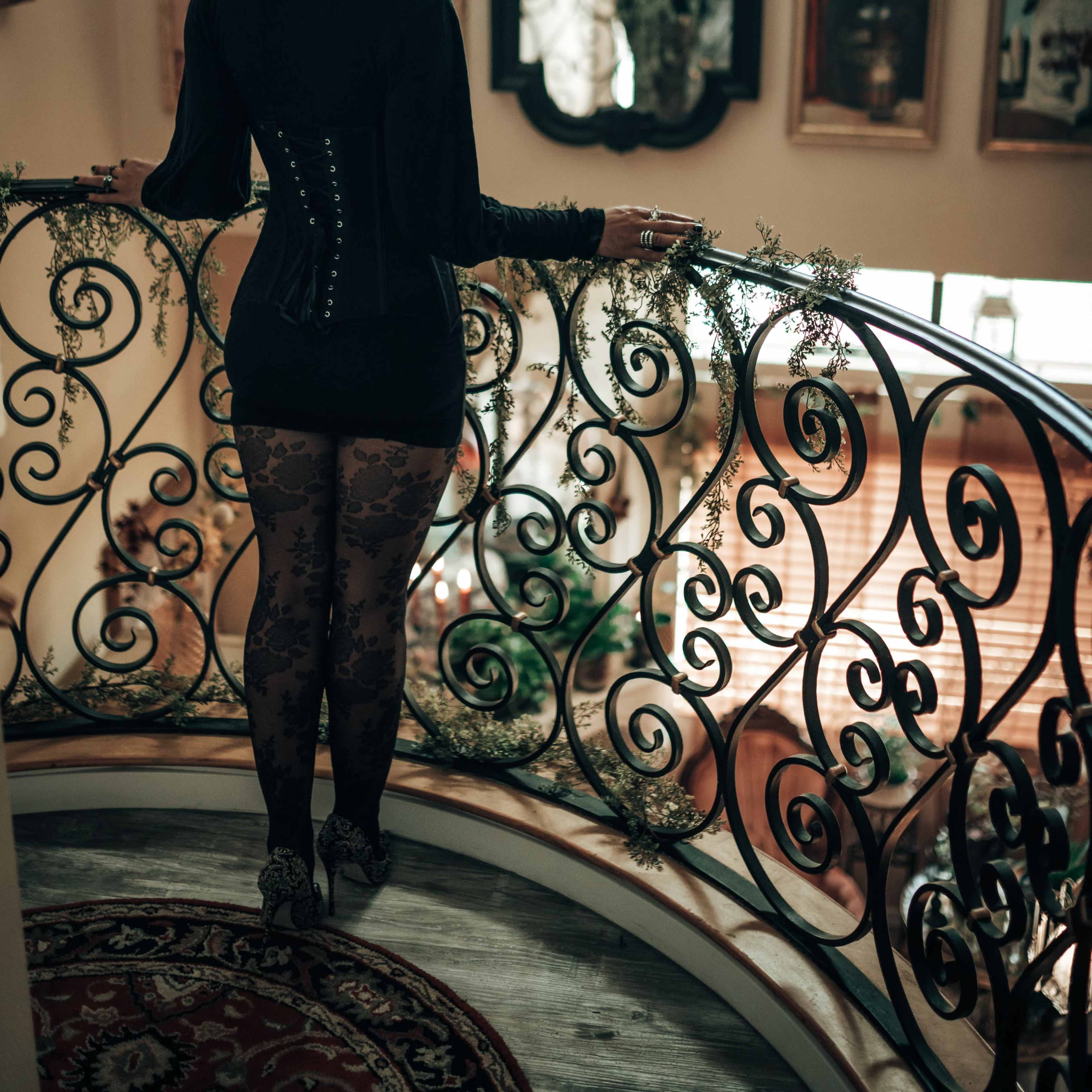 A person stands on a balcony overlooking a room adorned with mirrors and artwork.