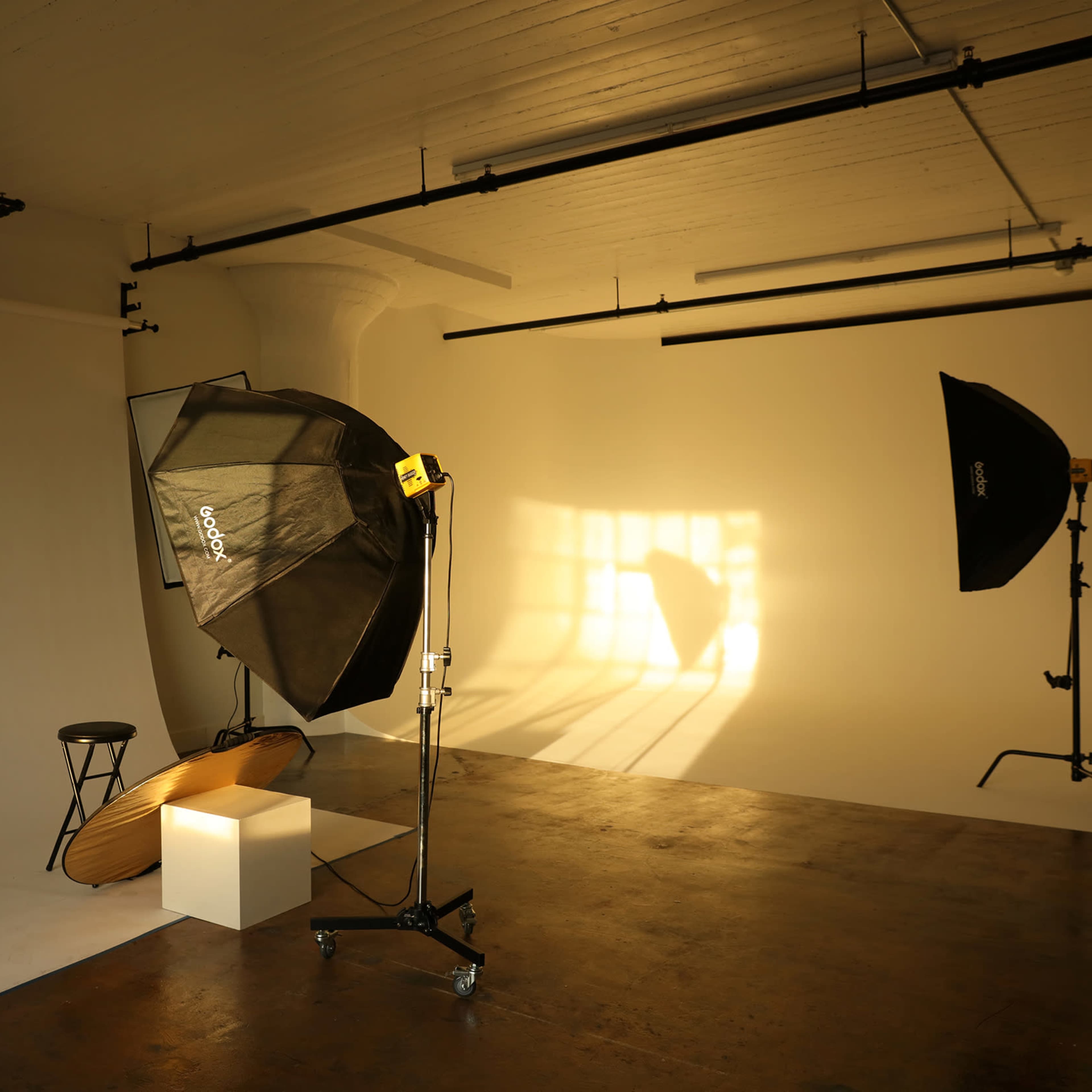 A photography studio with a light setup, backdrop, and a stool.