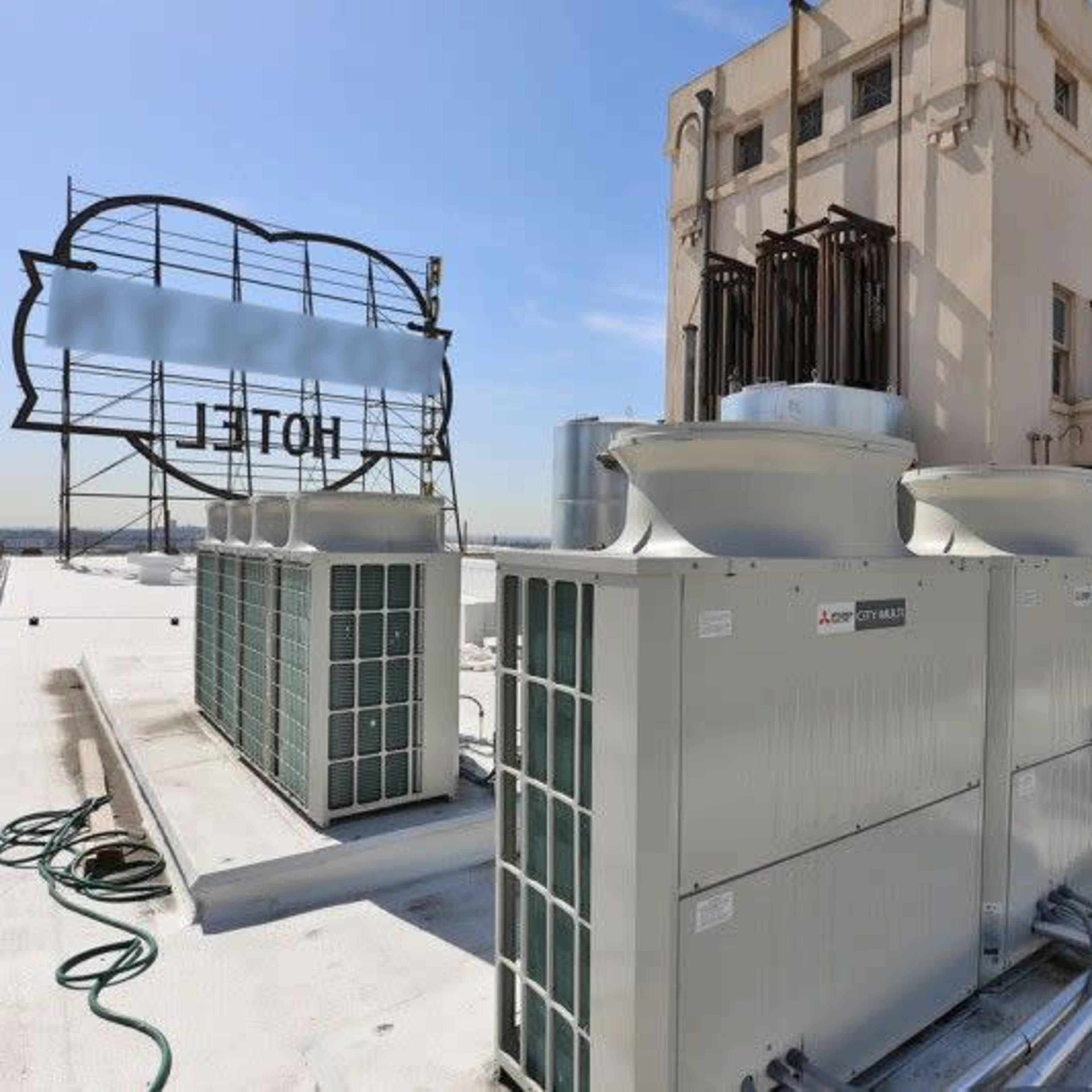 Rooftop HVAC units and cooling equipment on a building, with the city skyline visible in the background.
