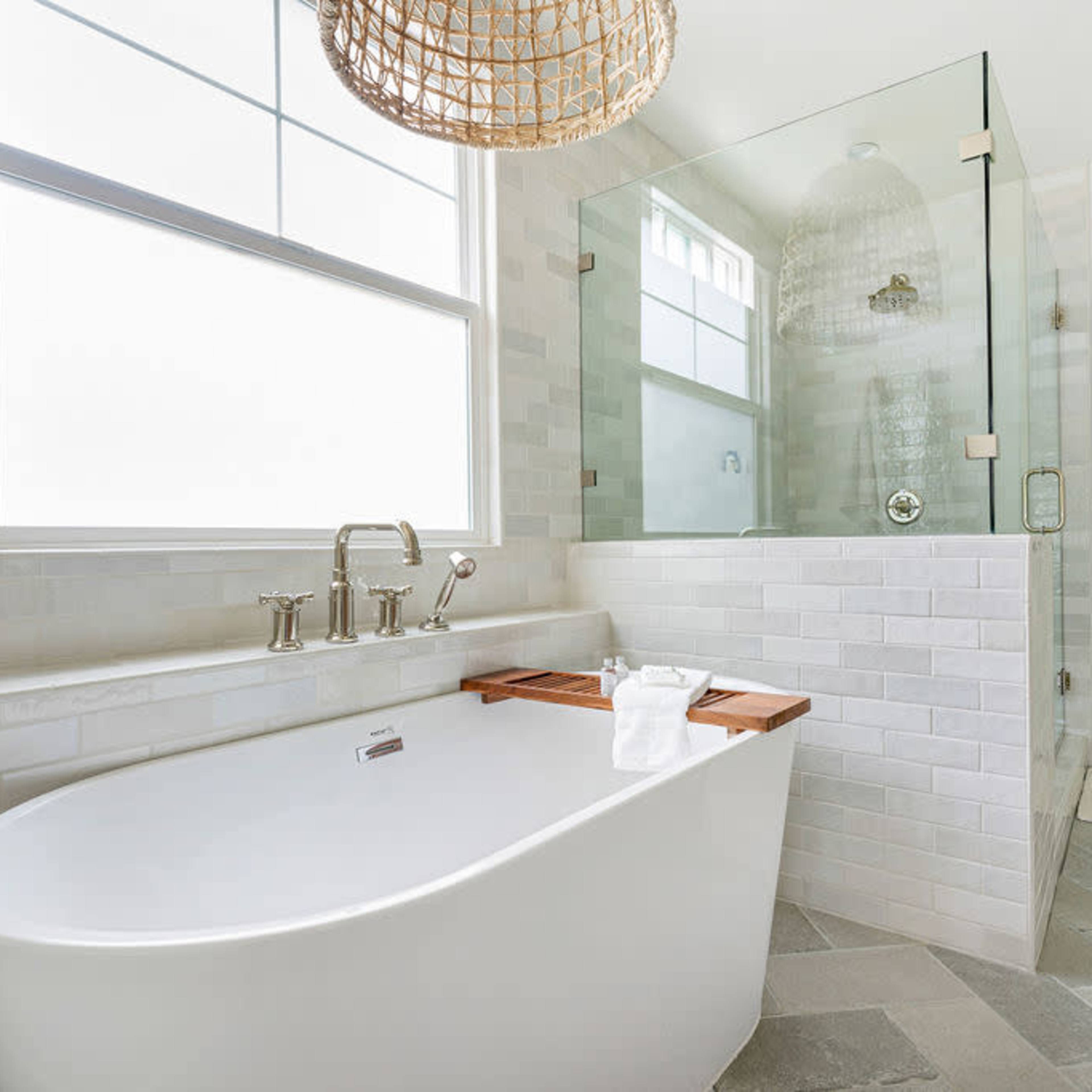 A modern bathroom with a freestanding tub, a glass shower enclosure, and a large window providing natural light.