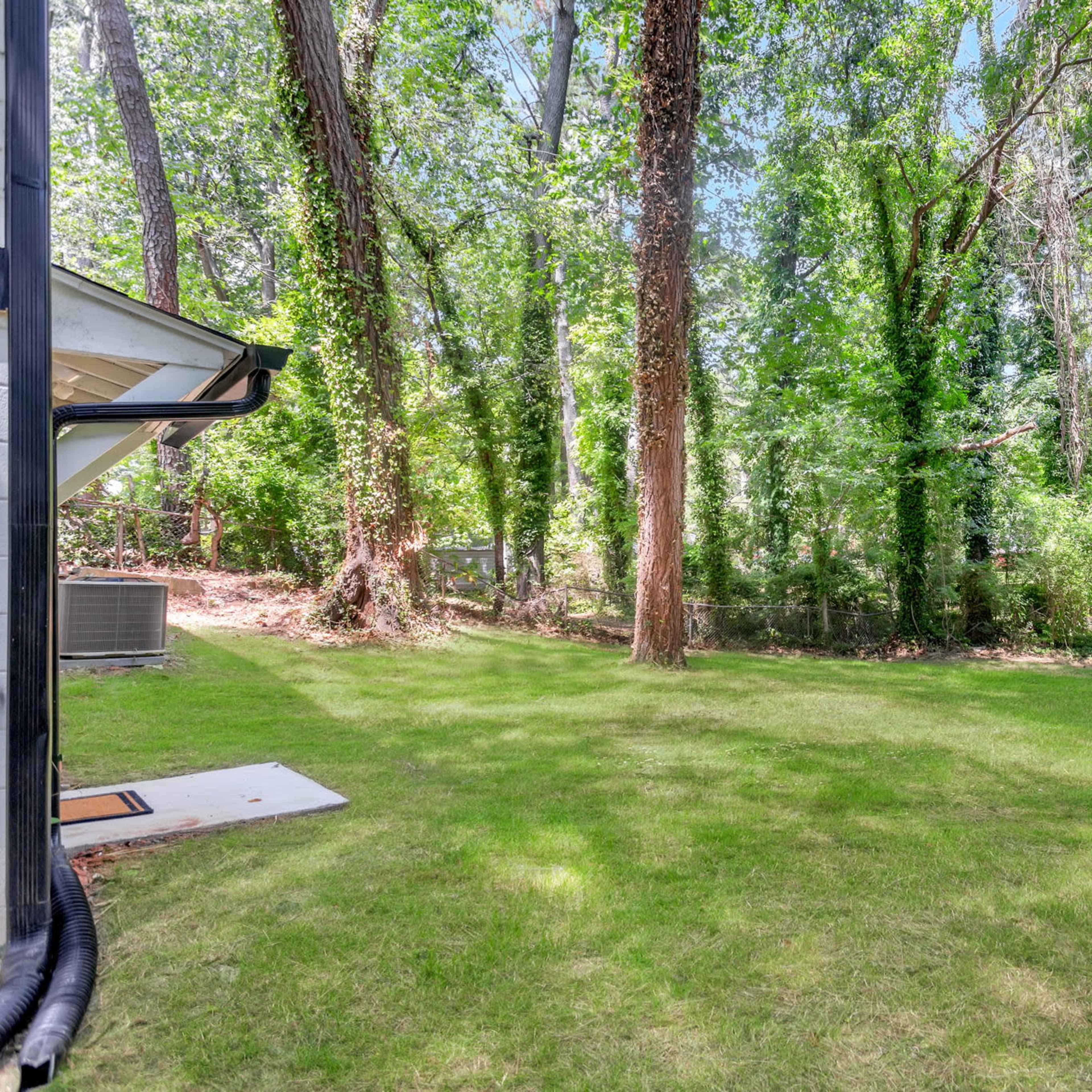 A grassy yard surrounded by dense trees and greenery.