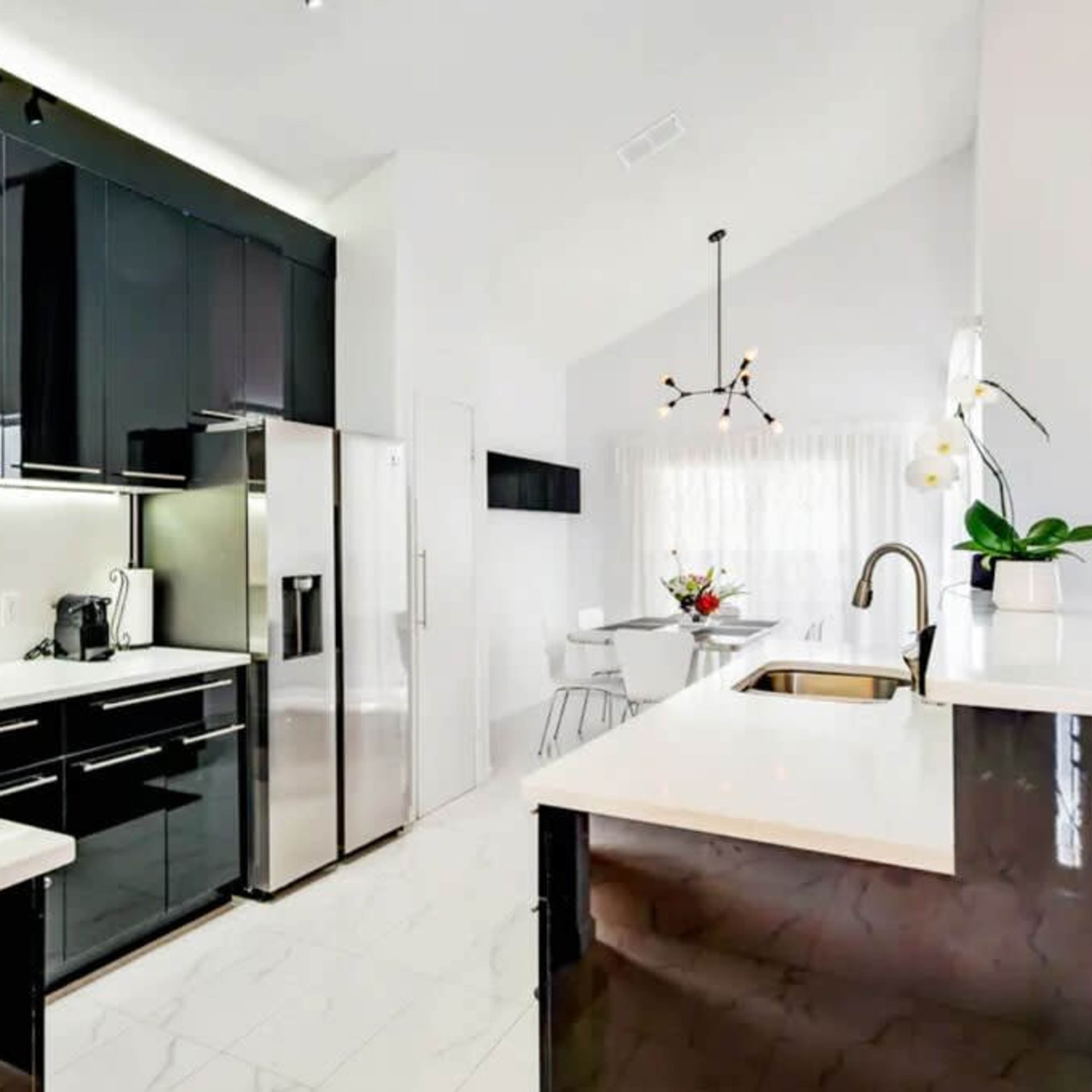 A modern kitchen featuring black cabinetry, stainless steel appliances, and a white marble countertop.